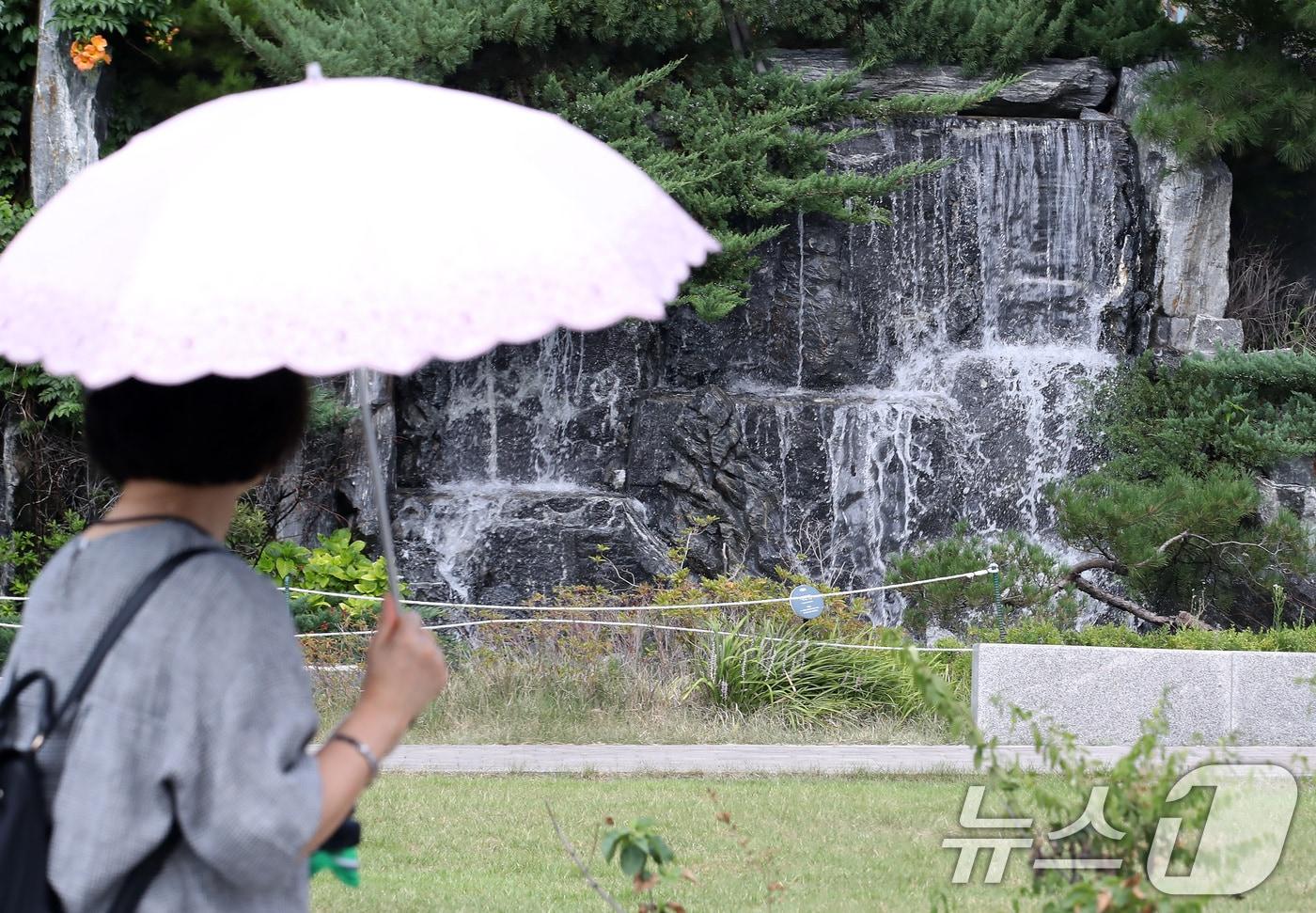대구 북구의 한 아파트 단지에서 양산을 쓴 시민이 인공폭포 앞을 지나고 있다. 2025.8.28/뉴스1 ⓒ News1 공정식 기자