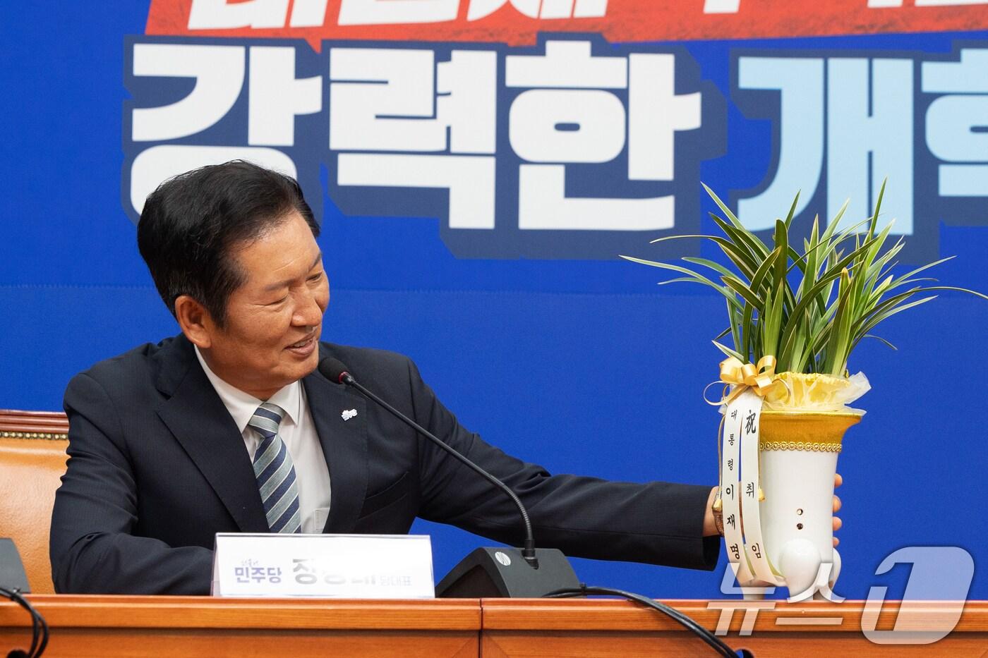 정청래 더불어민주당 신임 대표가 전날(4일) 오후 서울 여의도 국회에서 우상호 대통령실 정무수석으로부터 대통령 축하 난을 받은 뒤 화분을 살펴보고 있다. 2025.8.4/뉴스1 ⓒ News1 이승배 기자