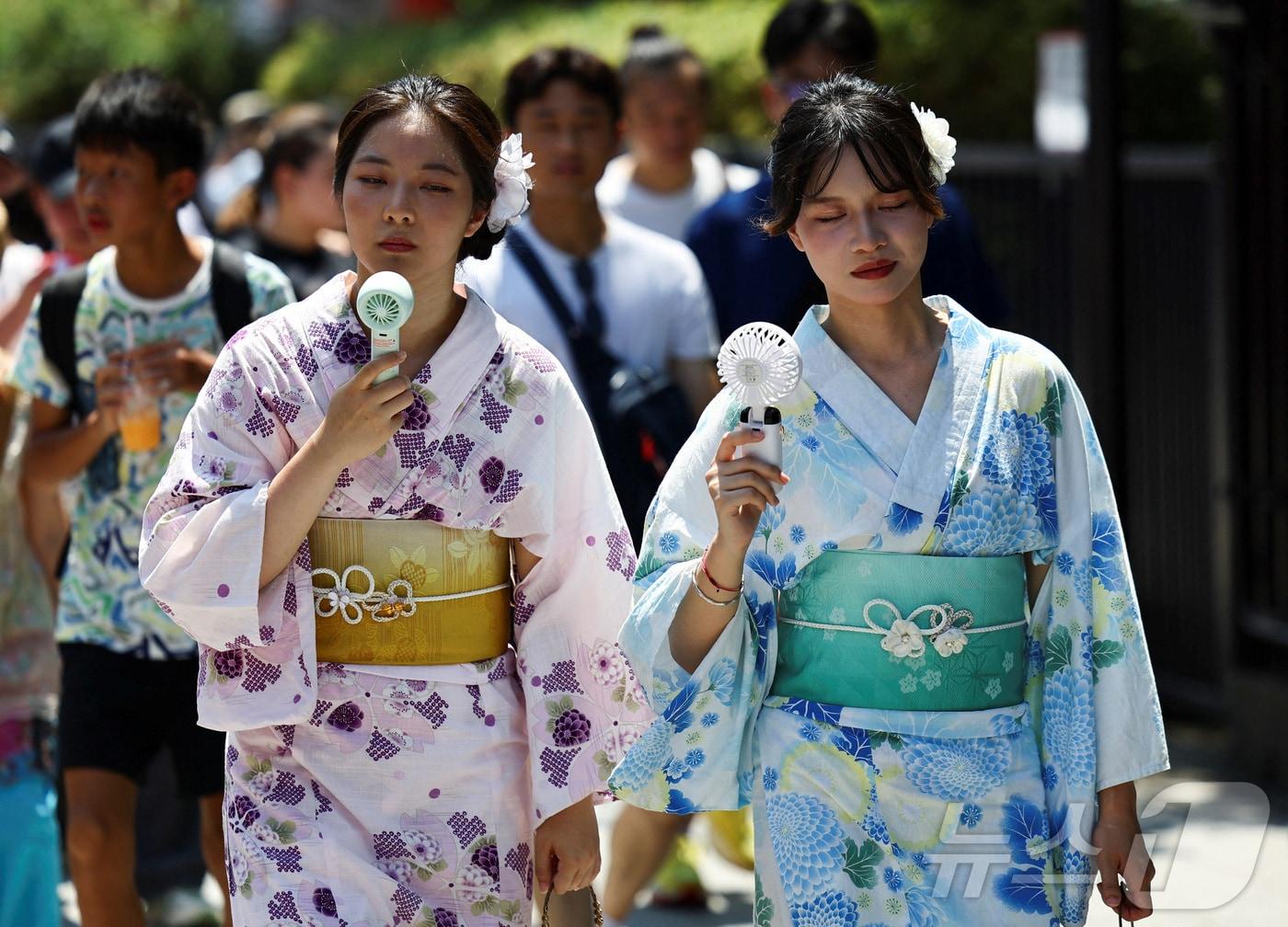 본문 이미지 - 5일 일본 도쿄 아카쿠사에서 유카타를 입은 여성들이 휴대용 선풍기로 땀을 식히고 있다. 이날 오후 도쿄도 오메시 기온은 40.3도를 기록했다. 2025.08.05 ⓒ 로이터=뉴스1 ⓒ News1 최종일 선임기자