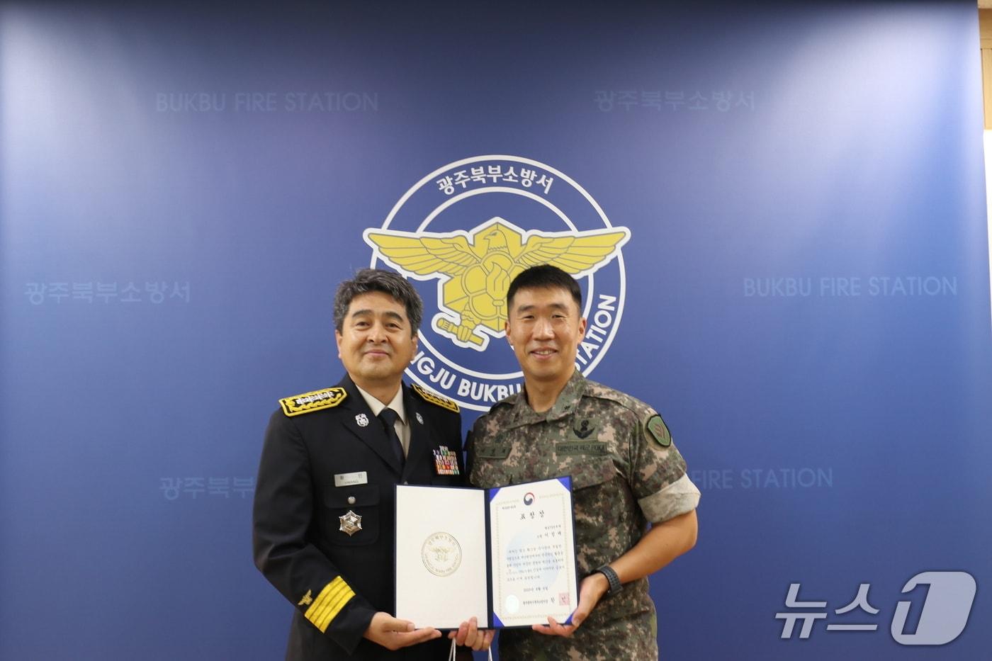 지난달 괴물폭우 속에 휩쓸릴 뻔한 대학생 2명을 무사 구조한 이정재 31사단 비호여단 소속 소령이 광주 북부소방서장으로부터 표창장을 수여받고 있다.&#40;광주 북부소방서 제공&#41; 2025.8.6