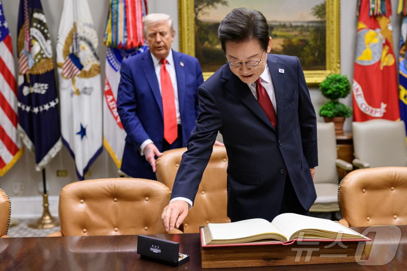 지난 8월 25일&#40;현지시간&#41; 이재명 대통령이 한미정상회담에 앞서 미 백악관 루즈벨트룸에서 방명록에 서명하려고 펜을 잡으려는 순간 도널드 트럼프 미국 대통령이 뒤에서 의자를 당겨 주고 있다. &#40;백악관 제공. 재판매 및 DB금지&#41; 2025.9.1/뉴스1 ⓒ News1 류정민 특파원