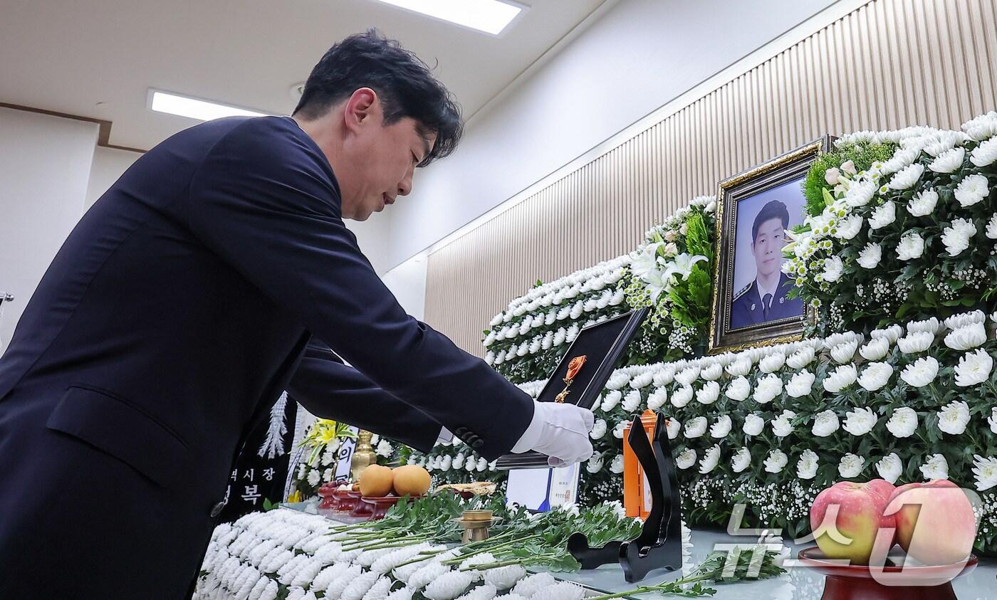 본문 이미지 - 강훈식 대통령 비서실장이 12일 인천 시내 한 장례식장에 마련된 故이재석 경사의 빈소를 찾아 조문한 후 훈장 추서판을 안치하고 있다.  2025.9.12/뉴스1 ⓒ News1 김성진 기자