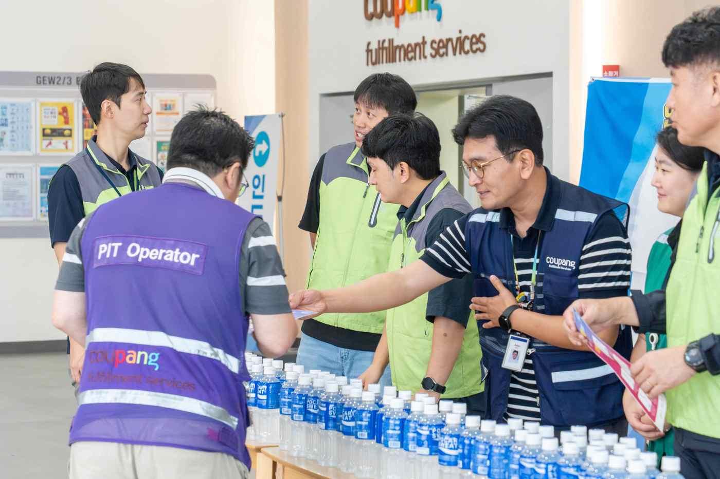 12일 쿠팡 금왕2·3센터에서 '안전한 일터 만들기' 합동 캠페인에 나선 고용노동부, 안전보건공단, 쿠팡풀필먼트서비스 관계자들이 직원들에게 이온 음료를 건네고 있다(쿠팡 제공).