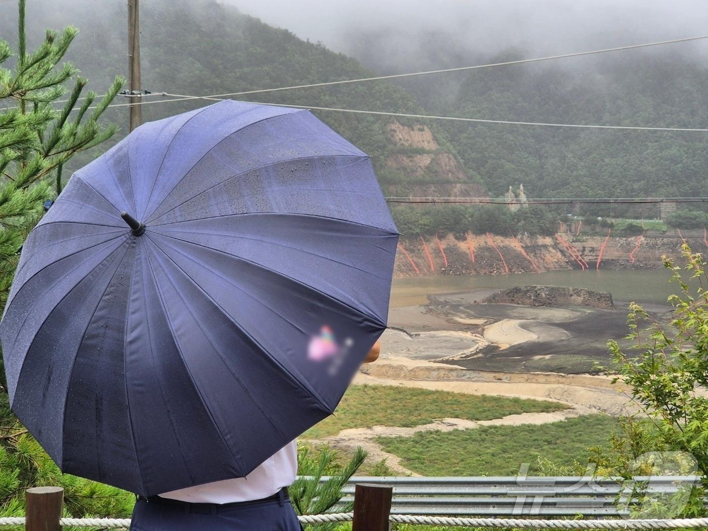 본문 이미지 - 극심한 가뭄을 겪고 있는 강원 강릉지역에 많은 비가 내린 지난13일 오전 우산을 쓴 시민이 마른 저수지에 내리는 단비를 바라보고 있다. 2025.9.13/뉴스1 ⓒ News1 윤왕근 기자