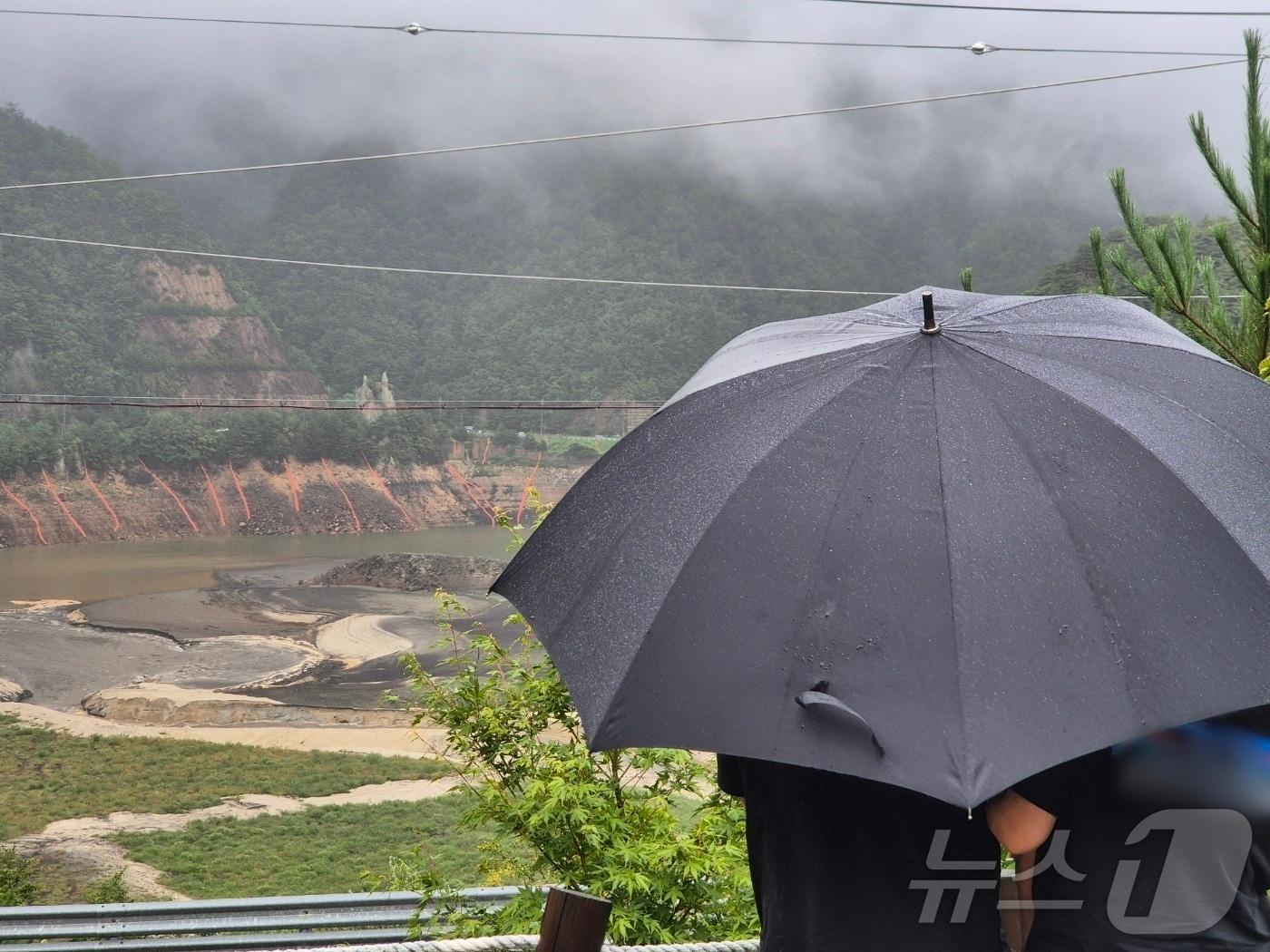 본문 이미지 - 극심한 가뭄을 겪고 있는 강원 강릉지역에 많은 비가 내린 13일 오전 우산을 쓴 시민이 마른 저수지에 내리는 단비를 바라보고 있다. 2025.9.13/뉴스1 ⓒ News1 윤왕근 기자