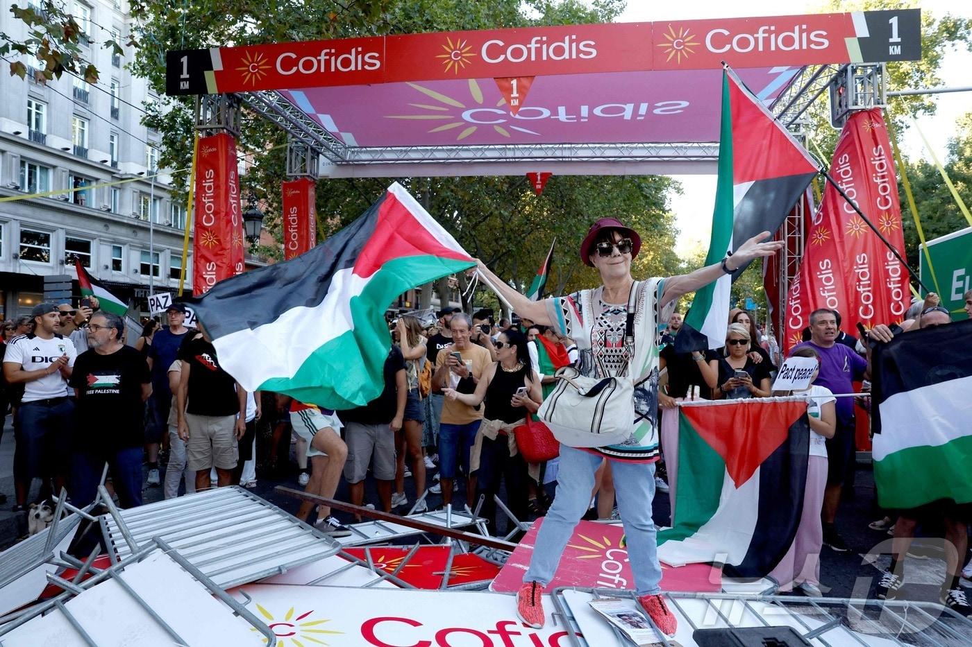     14일(현지시간) 스페인 수도 마드리드 아토차역 인근에서 열린 부엘타 아 에스파냐(Vuelta a Espa&ntilde;a) 결승 구간 도중 친팔레스타인 시위대가 도로를 점거하며 경기를 중단시킨 모습. 녹색과 붉은 연기가 자욱한 가운데 시위대는 "이스라엘 보이콧"을 외치며 바리케이드를 무너뜨리고 도로로 진입했다. 이날 시위에는 10만 명이 넘는 인원이 참여했으며, 경찰은 최루탄을 사용한 뒤 도로 진입을 허용했고 경기는 결승선 56km를 남기고 공식 취소됐다. 2025.9.14 ⓒ AFP=뉴스1