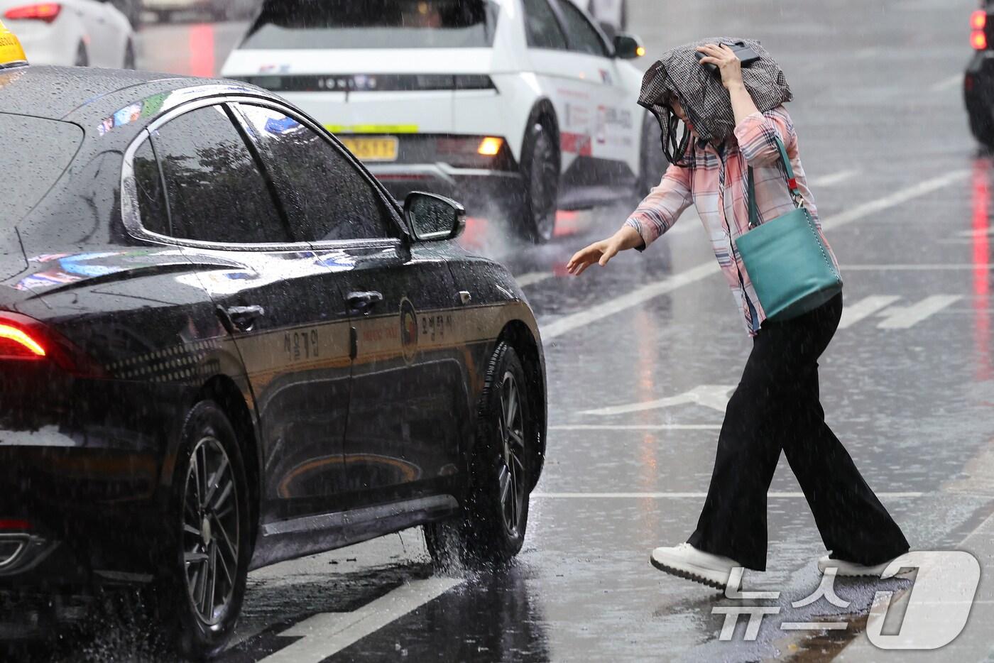 요란한 비가 내린 16일 오후 서울 종로구 광화문광장 인근을 지나는 시민이 가방으로 비를 피하며 급히 택시에 타고 있다. 2025.9.16/뉴스1 ⓒ News1 장수영 기자