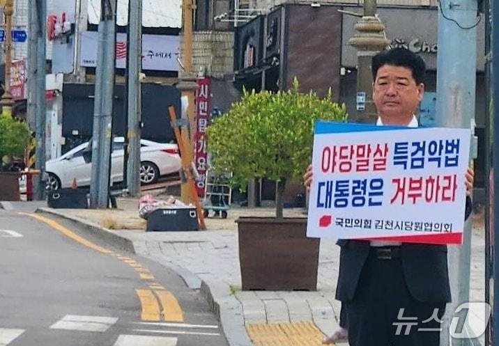 본문 이미지 - 나영민 김천시의장이 지난 15일 김천지역 거리에서 '야당 말살 특검 악법 대통령은 거부하라'는 손팻말을 들고 1인 시위를 벌이고 있다. (나영민 시의장 페이스북 갈무리/뉴스1)