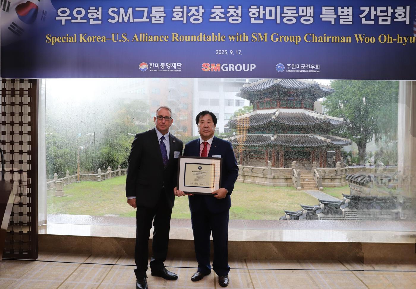 우오현 SM그룹 회장&#40;오른쪽&#41;이 지난 17일 서울 중구 웨스틴조선 서울에서 열린 한미동맹 특별 간담회에서 로버트 에이브럼스 주한미군전우회장&#40;전 한미연합사 사령관&#41;에게 감사패를 받은 뒤 기념촬영을 하고 있다. 감사패에는 한미연합사 사령관을 지낸 4성 장군 4인을 상징하는 별 16개와 사인이 담겼다. &#40;SM그룹 제공&#41;