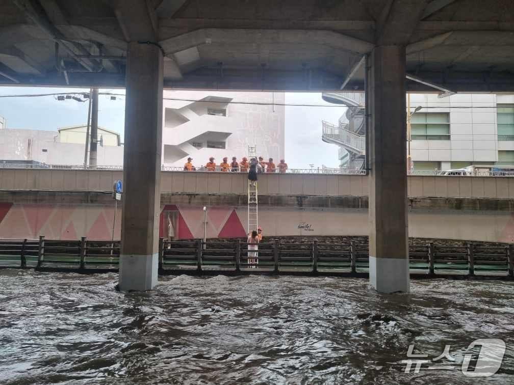 본문 이미지 - 2일 오후 부산 금정구 온천천에서 소방이 사다리를 이용해 고립된 여성을 구조하고 있다.&#40;부산소방재난본부 제공. 재판매 및 DB 금지&#41;
