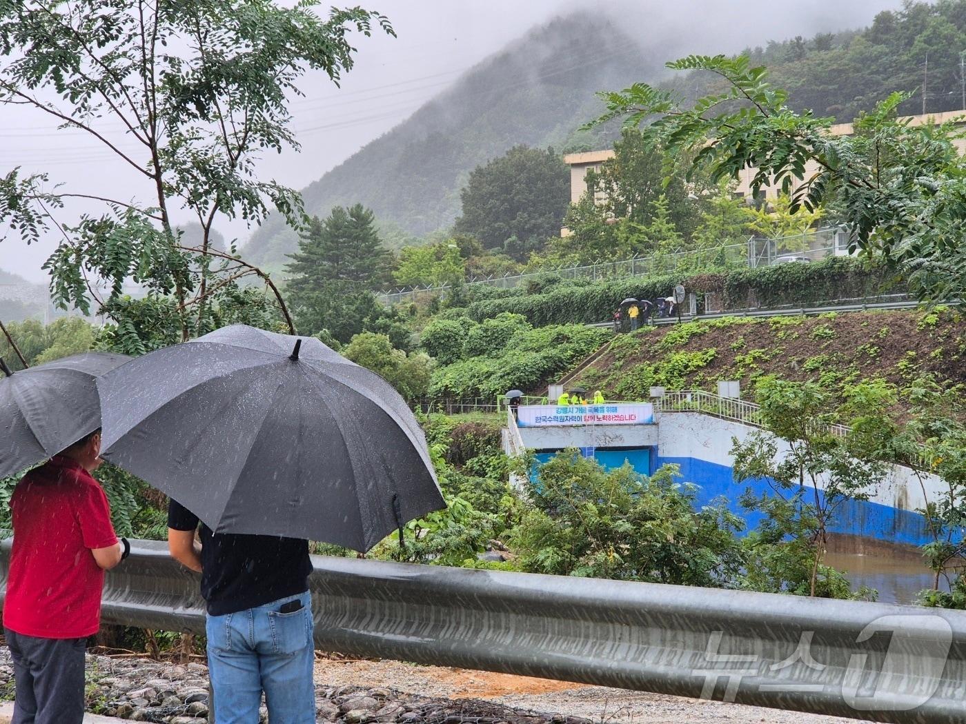 본문 이미지 - 강원 강릉에 단비가 내린 20일 오후 강릉 성산면 오봉리 한국수력원자력 강릉수력발전소에서 예정된 도암댐 도수관로 저류수 방류를 보기 위한 주민과 시 관계자들이 우산을 쓰고 현장을 바라보고 있다. 2025.9.20/뉴스1 ⓒ News1 윤왕근 기자