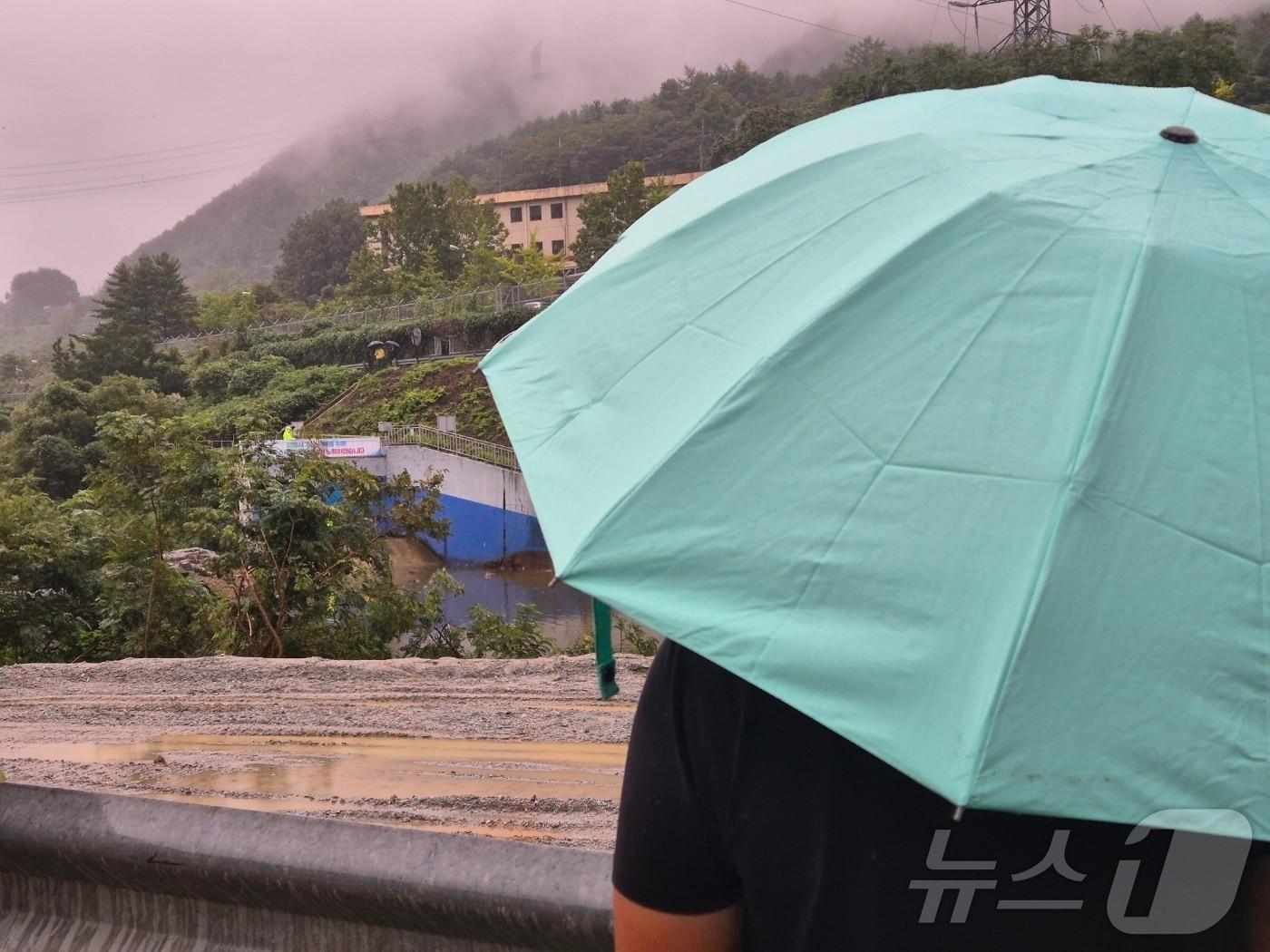본문 이미지 - 강원 강릉에 또 다시 단비가 내린 20일 오후 강릉 성산면 오봉리 한국수력원자력 강릉수력발전소에서 예정된 도암댐 도수관로 저류수 방류를 보기 위한 주민과 시 관계자들이 우산을 쓰고 현장을 바라보고 있다. 2025.9.20/뉴스1 ⓒ News1 윤왕근 기자