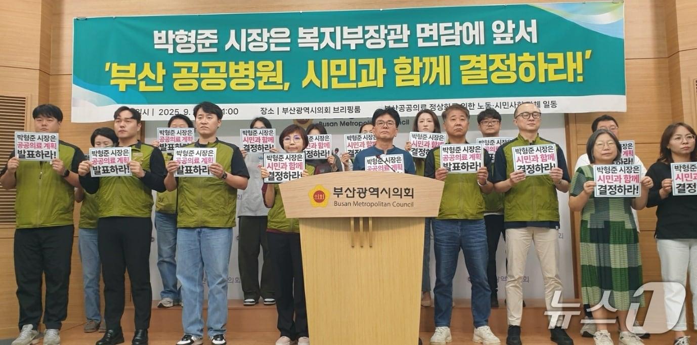 본문 이미지 - 부산공공의료정상화를 위한 노동·시민사회 단체 일동이 23일 오전 11시 시의회 브리핑룸에서 &#39;부산 공공병원을 시민과 함께 결정하라&#39;는 피켓을 들고 있다.2025.9.23/뉴스1 ⓒ News1 김태형 기자