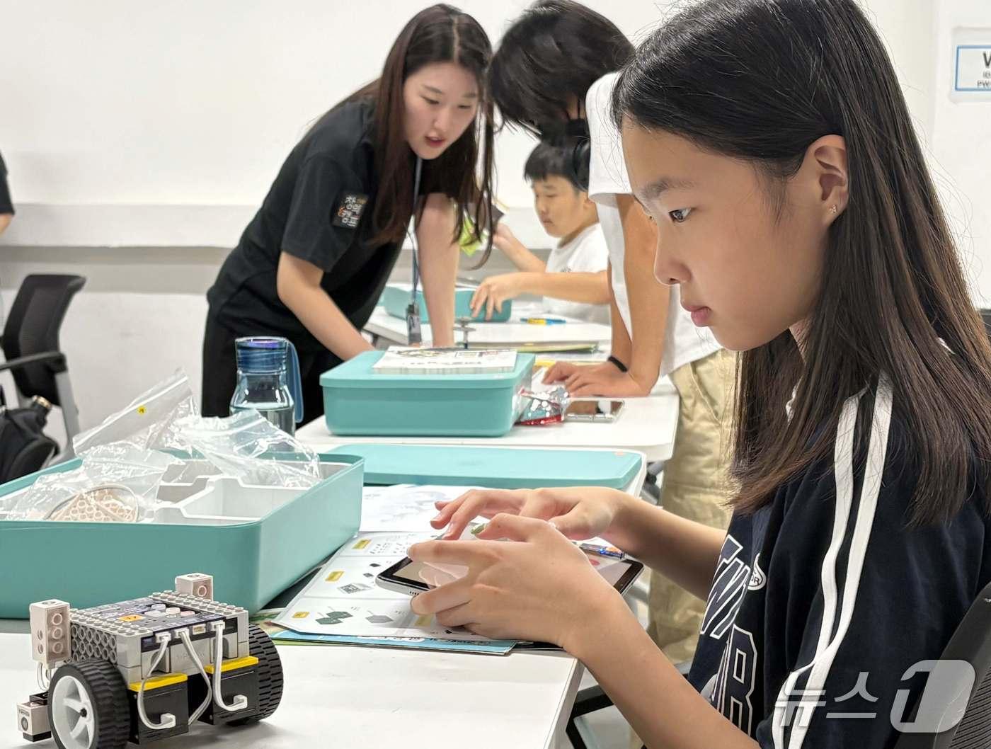 본문 이미지 - 참가학생이 네오씽카 교구를 활용해 제작한 자동차로 블록코딩을 실습하고 있다.&#40;CJ올리브네트웍스 제공&#41;