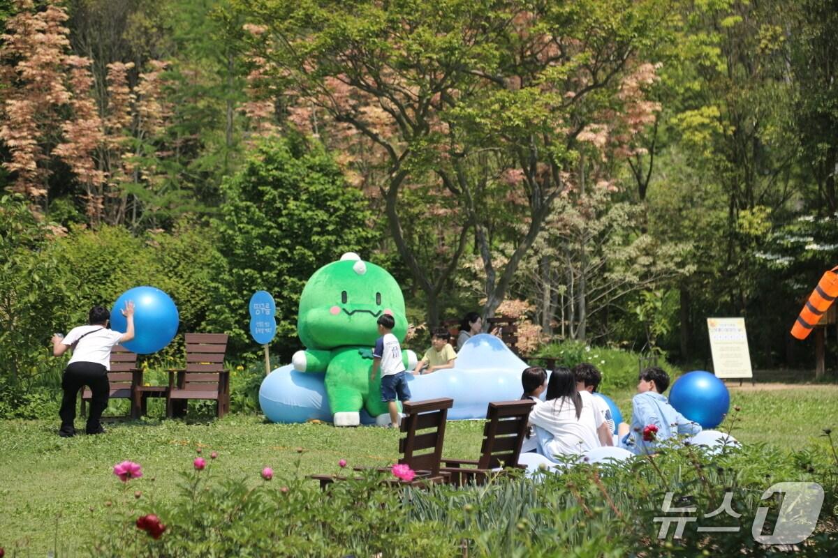 본문 이미지 - 천리포수목원을 찾은 어린이 탐방객이 수목원 마스코트 찰리푸스모건과 함께 친환경 놀이터에서 놀고 있다.(수목원 제공. 재판매 및 DB금지)2025.9.25/뉴스1