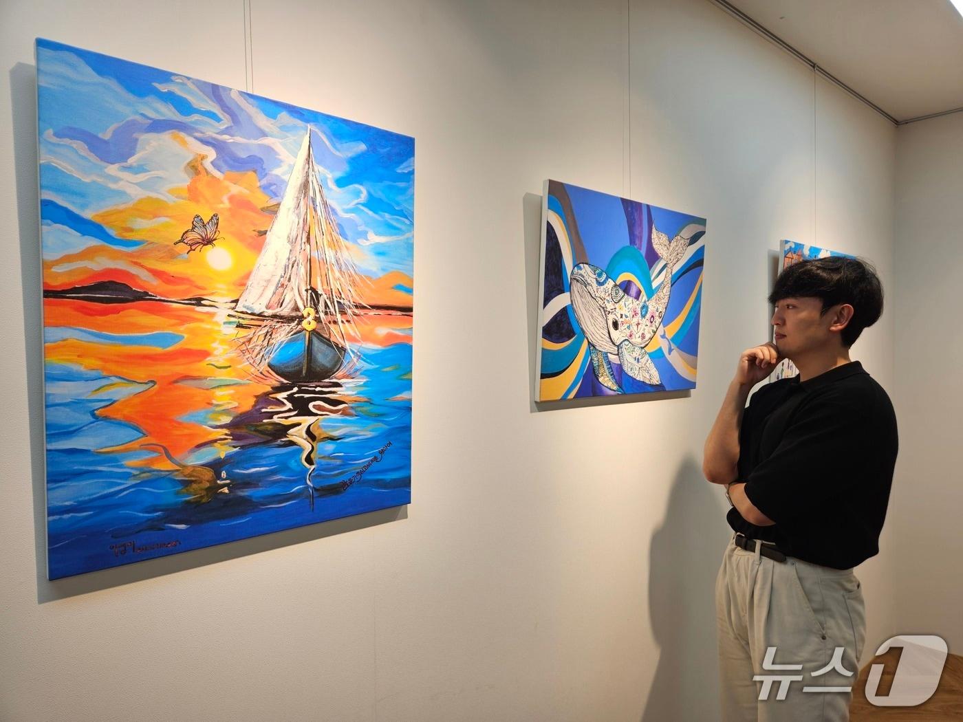 본문 이미지 - 현대제철 직원이 ㈜올모용인 사업장에 걸린 소속 발달장애인 작가들의 작품을 감상하고 있다. (현대제철 제공) 