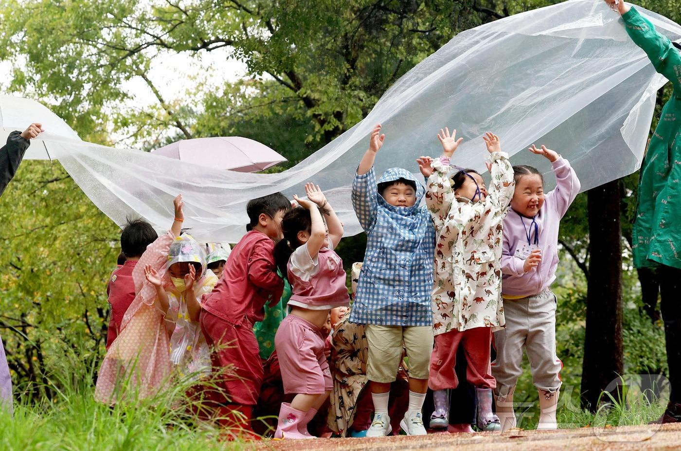비가 내린 25일 광주 북구 문흥동 문화근린공원 유아숲체험원에서 열린 숲체험 프로그램에 참가한 매곡어린이집 아이들이 숲해설사와 비닐에 떨어지는 빗소리를 들으며 자연을 느끼고 있다.&#40;광주 북구 제공. 재판매 및 DB 금지&#41; 2025.9.25/뉴스1 