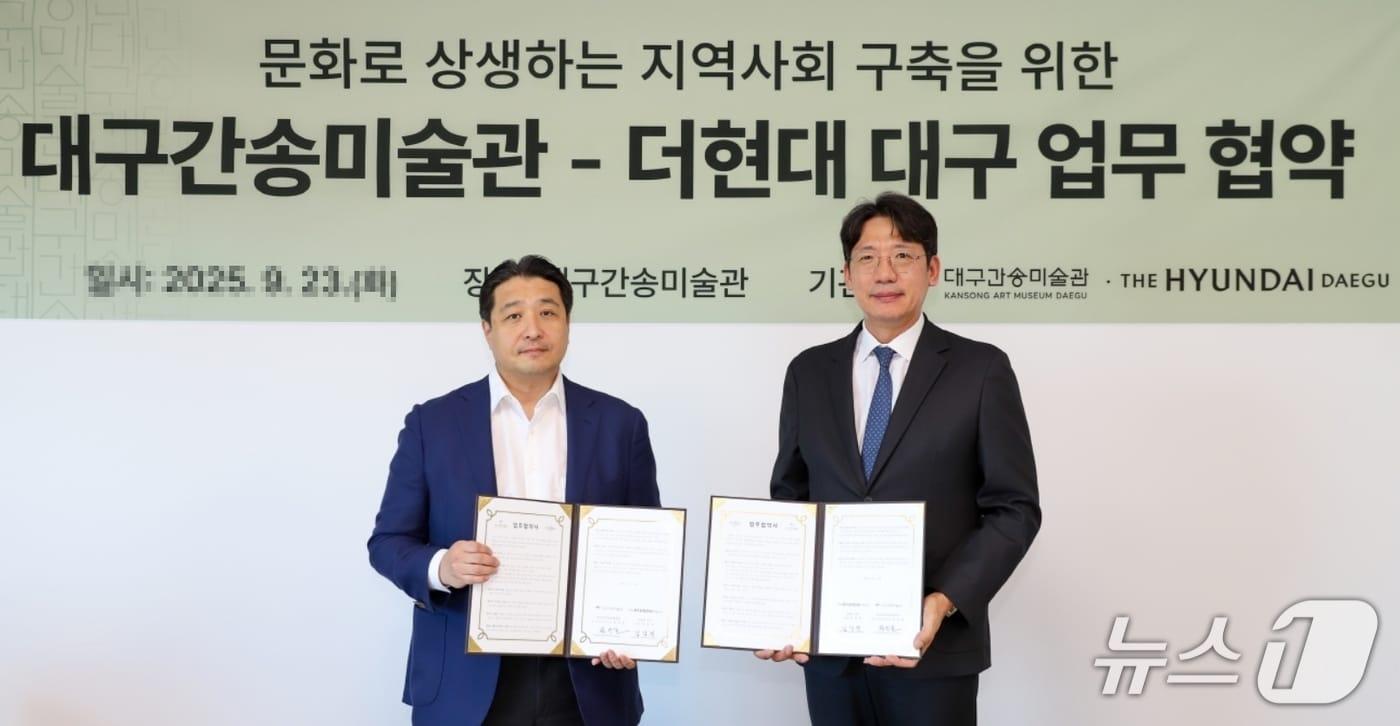김강진 더현대 대구 점장(오른쪽)과 전인건 대구간송미술관장이 문화로 상생하는 지역사회 구축과 관람객의 문화향유 확산을 위한 업무협약을 체결한 후 협약서를 펼쳐 보이고 있다.(더현대 대구 제공. 재판매 및 DB 금지)