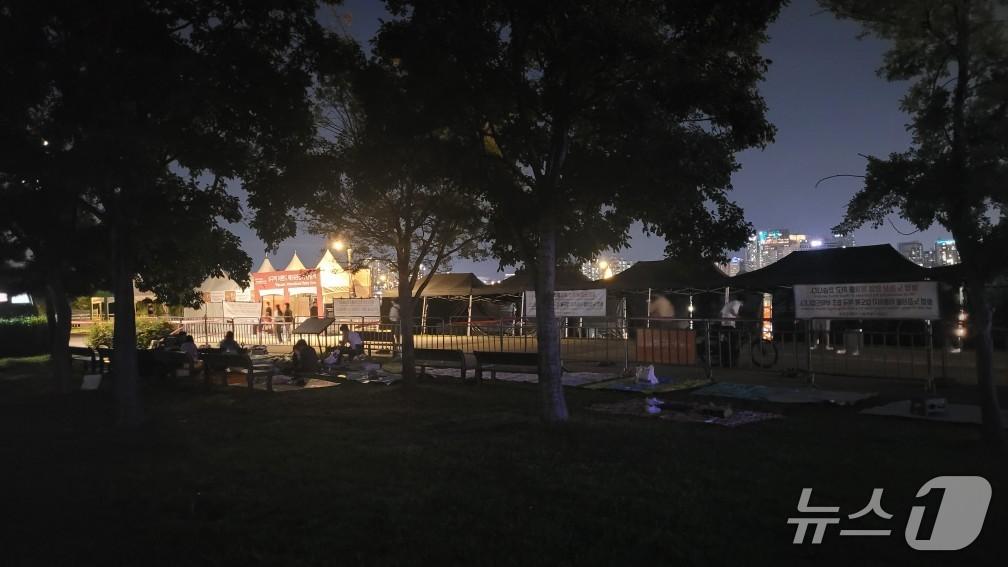 본문 이미지 - 26일 오후 9시 서울 영등포구 여의도한강공원 일대에서 시민들이 돗자리를 펴놓고 27일 열리는 '2025 서울 세계불꽃축제 '관람 자리를 지키고 있다.