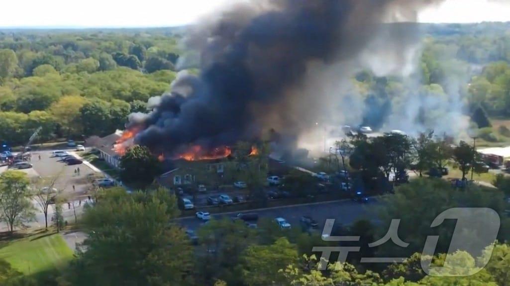 본문 이미지 - 28일(현지시간) 미시간주 그랜드블랑 타운십에 위치한 예수 그리스도 후기 성도 교회에서 발생한 화재 현장을 드론으로 촬영한 영상의 한 장면. 해당 영상은 소셜미디어 X에서 Julie J(@MALKOWSKI6APRIL)가 공유한 것으로, 차량 돌진과 총격 사건으로 교회 건물에서 연기가 치솟는 모습이 담겨 있다. 2025.9.28ⓒ AFP=뉴스1
