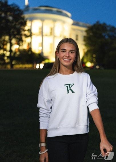 본문 이미지 - 도널드 트럼프 미국 대통령의 손녀 카이 트럼프가 자신의 브랜드 로고가 찍힌 스웨트셔츠를 입고 백악관 앞에서 홍보용 사진을 촬영하고 있다. (카이 트럼프 인스타그램)