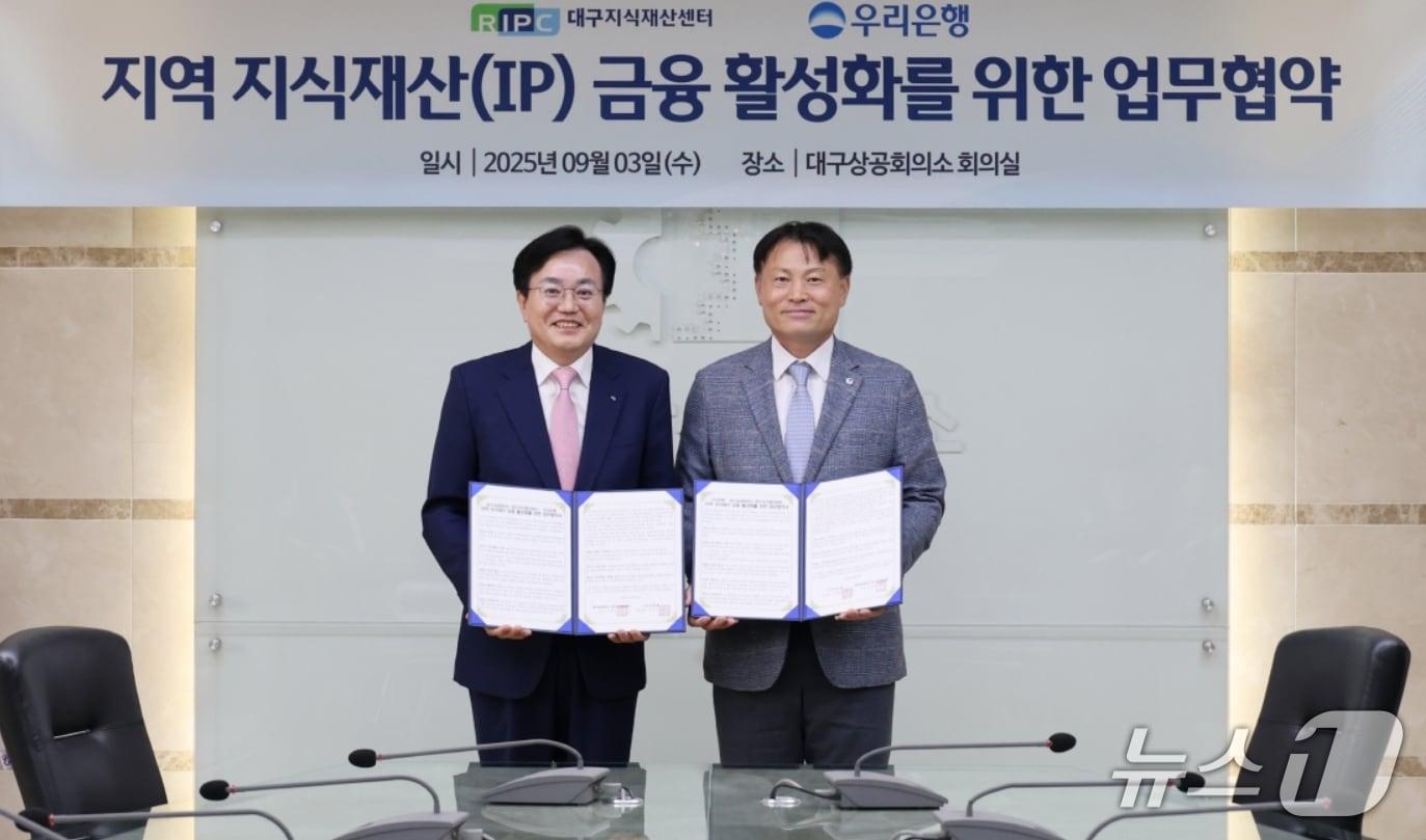 본문 이미지 - 이상길 대구상공회의소 상근부회장&#40;왼쪽&#41;과 박상형 우리은행 대구경북 서부영업본부장이 지식재산&#40;IP&#41; 금융활성화를 위한 업무협약을 체결한 뒤 협약서를 펼쳐 보이고 있다.&#40;대구상의 제공. 재판매 및 DB 금지&#41;