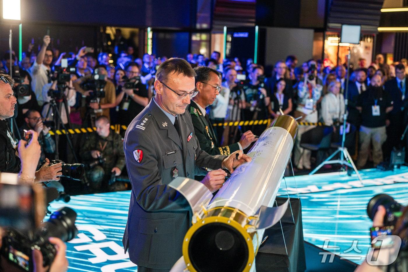 폴란드 키엘체 국제방위산업전시회&#40;MSPO 2025&#41;에서 열린 천무 유도탄 생산을 위한 한화에어로스페이스와 폴란드 WB기업의 현지 합작법인 계약식에서 한국과 폴란드 양국 정부·군·업계 관계자들이 성공적인 방산 협력을 축하하며 천무 모형탄에 서명하는 모습&#40;한화에어로스페이스 제공&#41; 2025.9.3/뉴스1