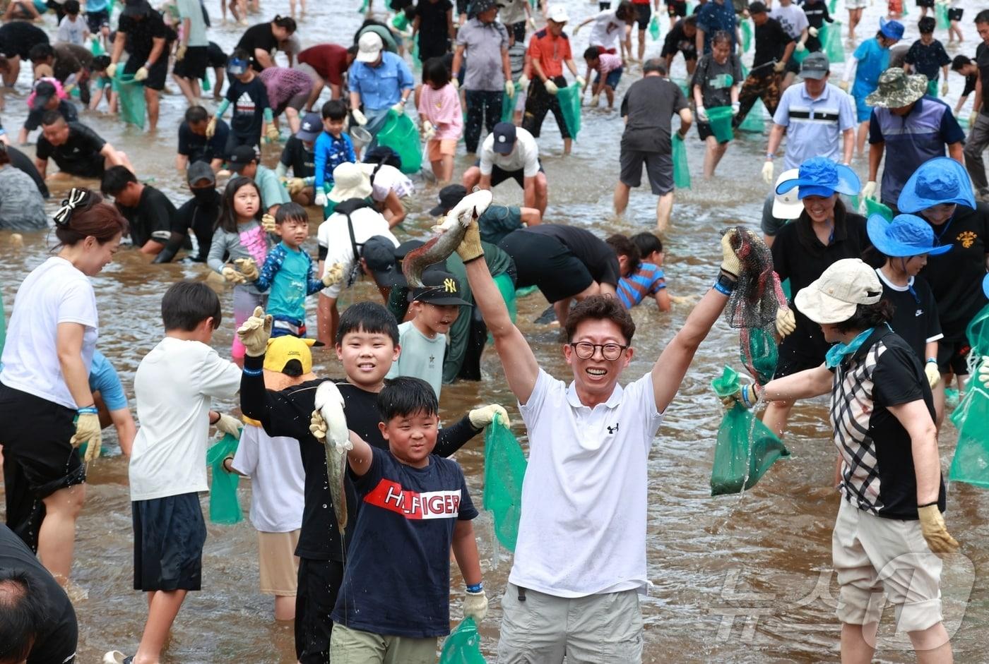 2025 괴산고추축제 체험 프로그램인 '고추물고기를 잡아라' 참가자가 메기를 잡은 뒤 번쩍 들어 올려 환호성을 지르고 있다.2025.09.06.ⓒ 뉴스1 2025.9.6/뉴스1 ⓒ News1 이성기 기자