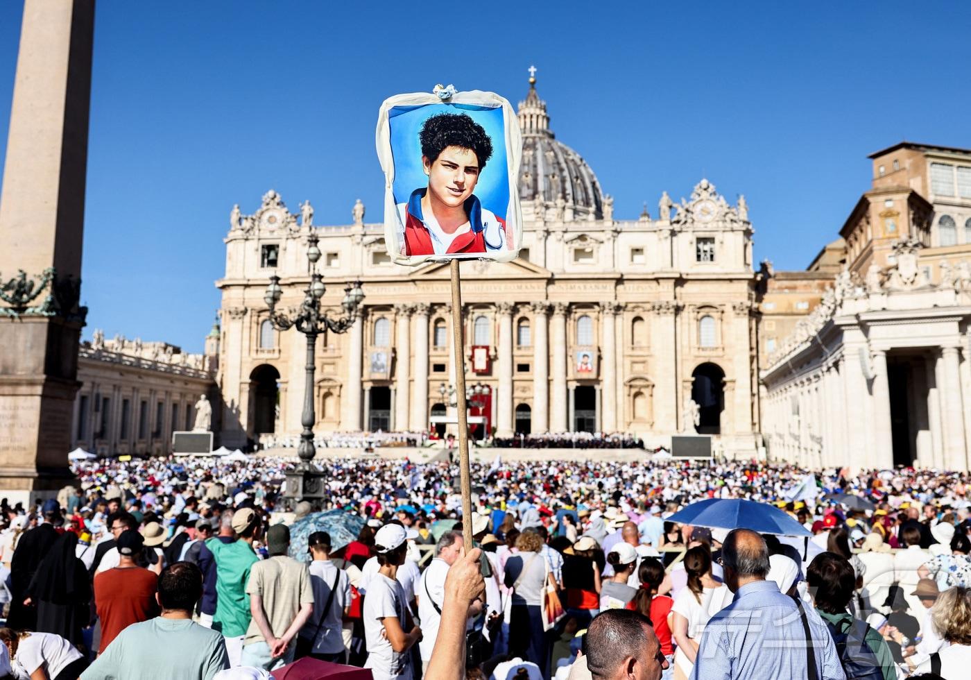 바티칸의 성베드로 광장에서 7일 영국 태생 이탈리아 소년 카를로 아쿠티스와 피에르 조르조 프라사티의 성인 시성을 위한 미사가 집전되고 있다. 이날 약 6만명의 인파가 쏠렸으며, 한 참석자가 아쿠티스의 사진을 높이 들어올리고 있다. 2025.9.7 ⓒ 로이터=뉴스1 ⓒ News1 강민경 기자