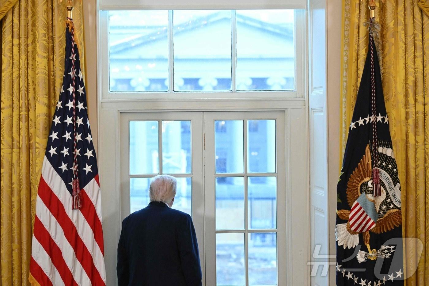 본문 이미지 - 도널드 트럼프 미국 대통령이 9일(현지시간) 미국 워싱턴DC 백악관 이스트룸에서 미국 주요 석유기업 경영진들과 회담을 앞두고 새 연회장 공사 현장을 창문 너머로 살펴보고 있다. 2026.01.09. ⓒ AFP=뉴스1