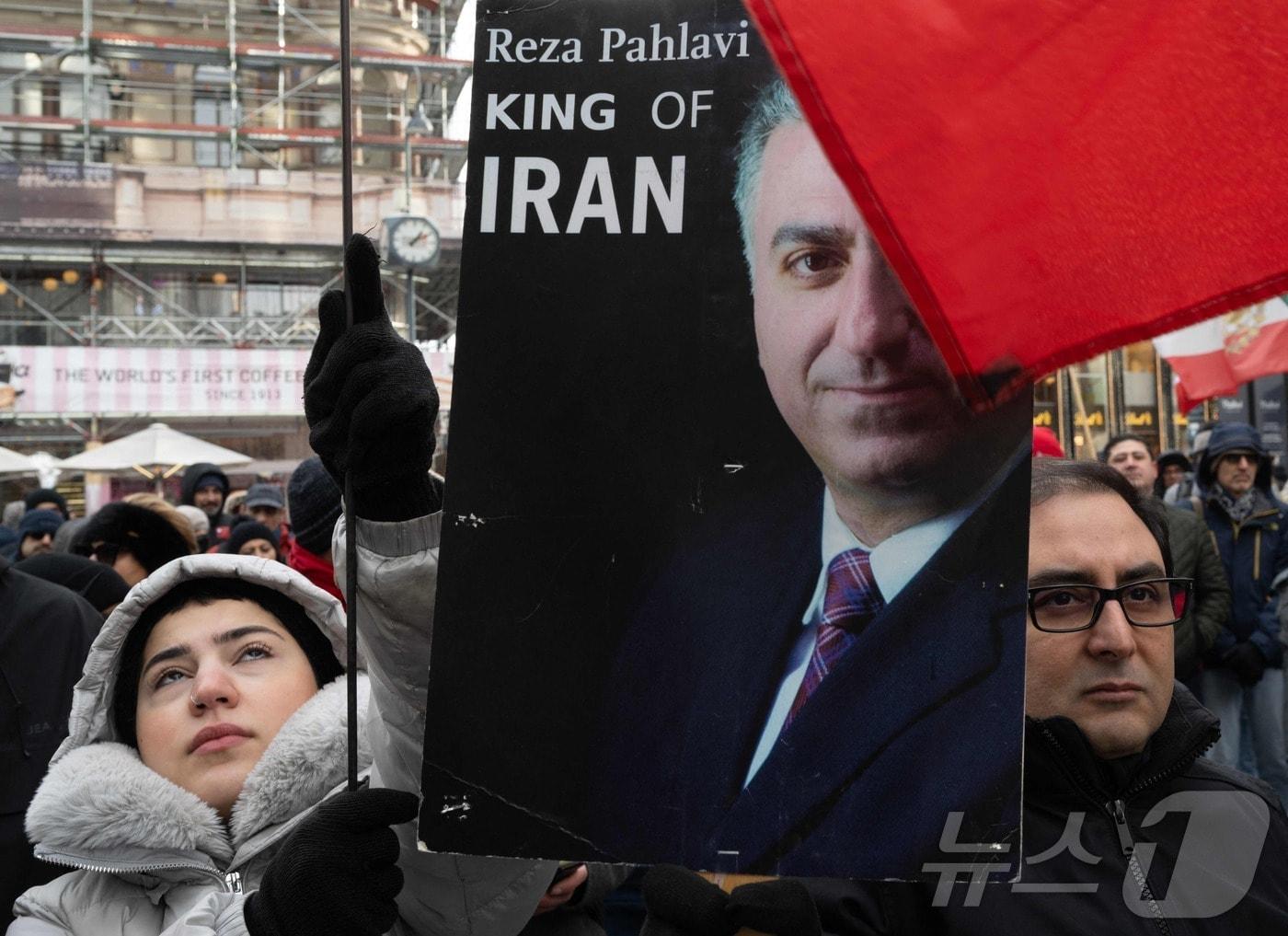 본문 이미지 - 11일(현지시간) 오스트리아 빈에서 이란의 반정부 시위를 지지하는 시민들이 이란의 마지막 국왕(샤)의 망명 중인 아들 레자 팔라비의 사진을 들어 올리고 있다. ⓒ AFP=뉴스1