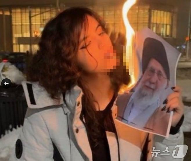 본문 이미지 - 이란의 한 여성이 히잡을 벗은 뒤 아야톨라 알리 하메네이 최고지도자의 사진을 담뱃불로 태우고 있다. (엑스 갈무리)