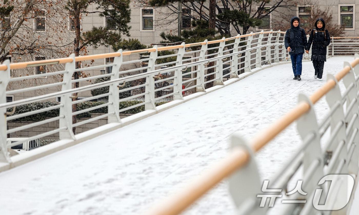 눈이 내리는 12일 서울 마포구 인근 육교에서 외국인 관광객들이 발걸음을 옮기고 있다. 2026.1.12/뉴스1 ⓒ News1 이호윤 기자