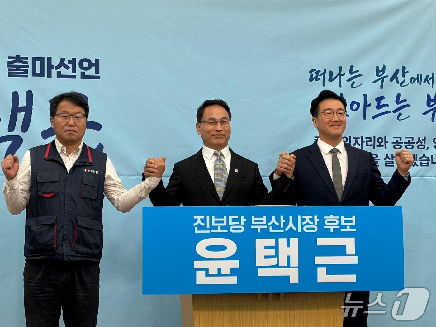 본문 이미지 - 윤택근 전 민주노총 위원장 권한대행(가운데)이 13일 부산시의회 브리핑룸에서 부산시장 진보당 후보 출마선언을 한 이후 김재남 민주노총 부산본부장(왼쪽), 노정현 진보당 부산시당위원장과 기념촬영을 하고 있다. 2026.1.13 ⓒ 뉴스1 홍윤 기자