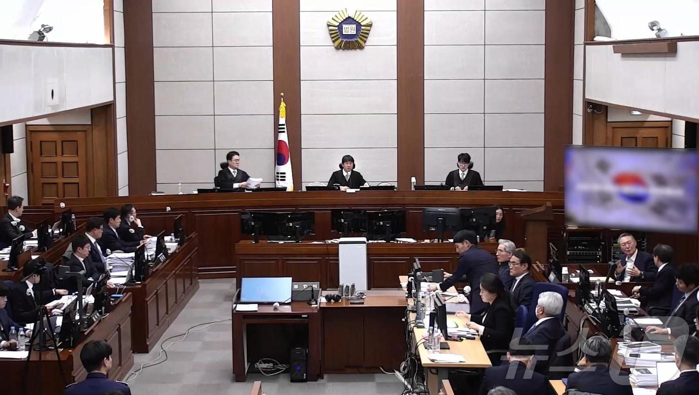 윤석열 전 대통령이 13일 오후 서울 서초구 서울중앙지방법원에서 진행된 내란 우두머리 혐의 2차 결심공판에 출석해 자리에 앉아 윤갑근 변호사와 대화를 하고 있다. (서울중앙지방법원 제공 영상 캡쳐. 재판매 및 DB 금지) 2026.1.13/뉴스1