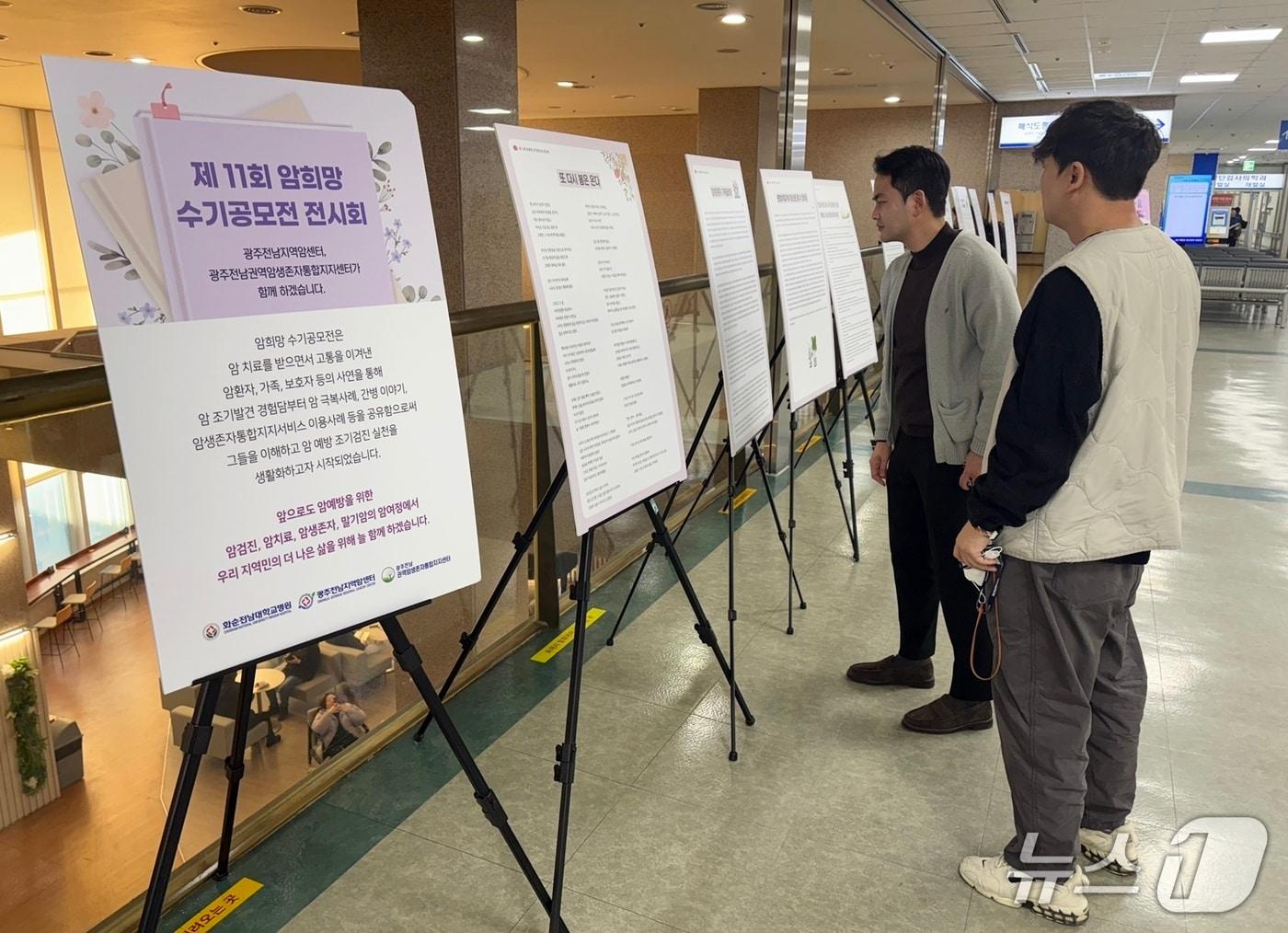 본문 이미지 - 화순전남대학교병원 2층 로비에 전시된 ‘제11회 암 희망 수기’ 공모작을 직원들이 바라보고 있다.(화순전남대병원 제공. 재판매 및 DB 금지) 2026.1.14/뉴스1