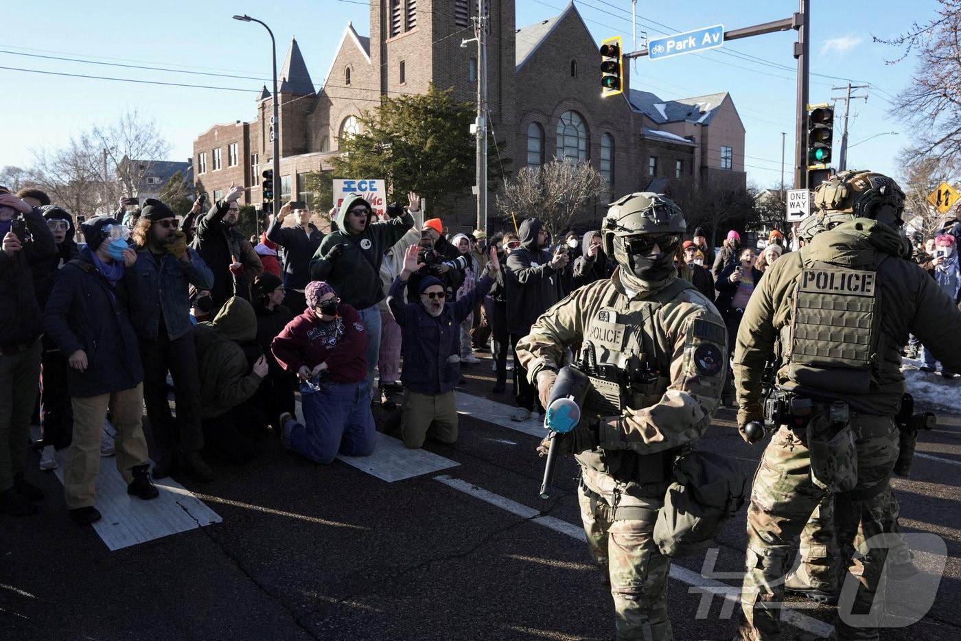 본문 이미지 - 13일(현지시간) 미국 미네소타주 미니애폴리스에서 경찰과 시민들이 대치하고 있다. 일부 시민은 항의의 뜻으로 무릎을 꿇고 있다. 2026.01.13. ⓒ 로이터=뉴스1 ⓒ News1 권영미 기자