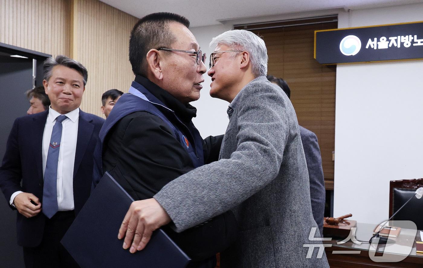 14일 서울 영등포구 서울지방노동위원회에서 열린 특별조정위원회 2차 사후 조정회의에서 서울 시내버스 노사가 임금협상에 극적으로 합의한 뒤 박점곤 서울시버스노동조합 위원장과 김정환 서울시버스사업조합 이사장이 포옹을 하고 있다. 2026.1.15/뉴스1 ⓒ News1 박지혜 기자