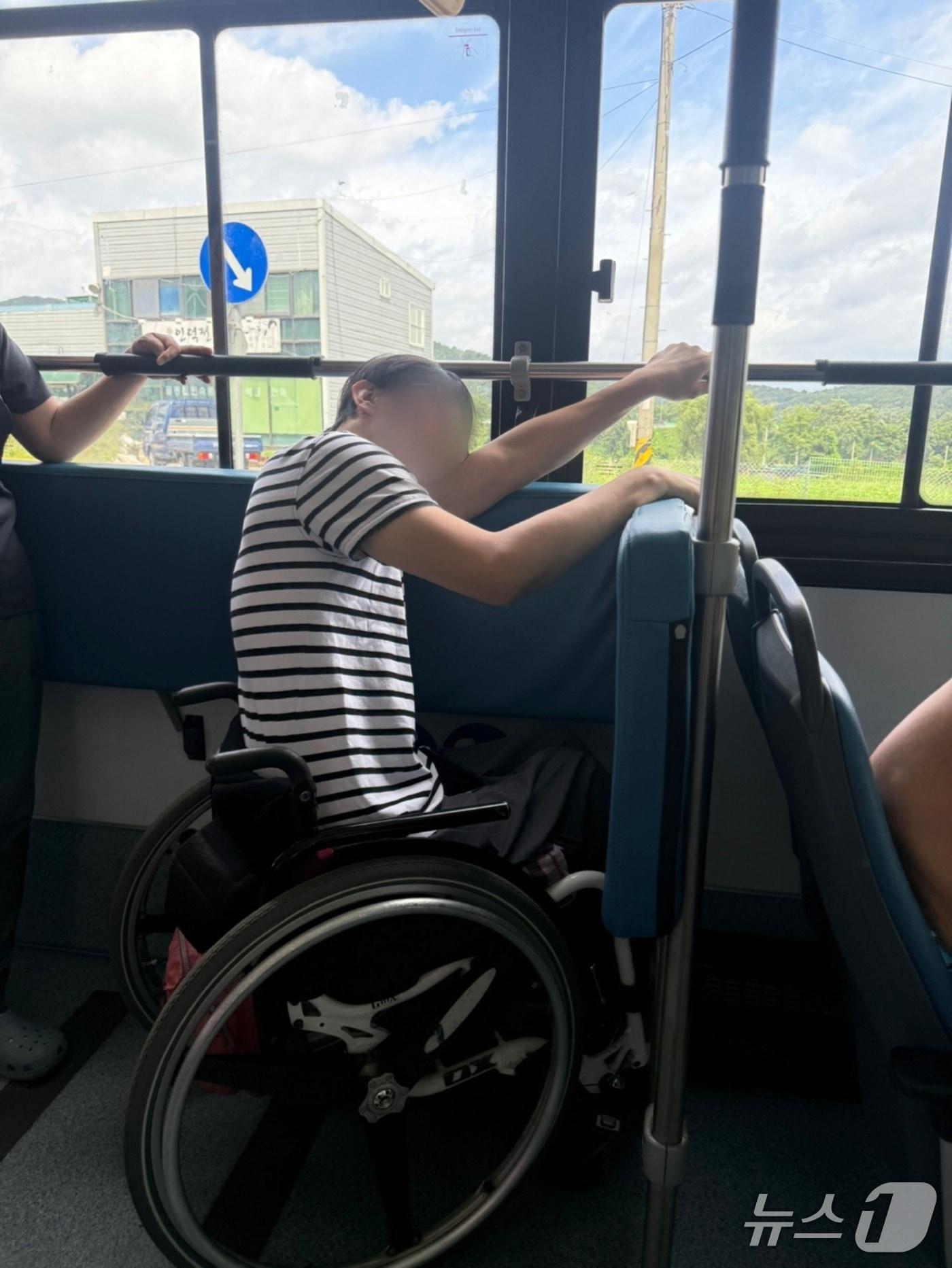 본문 이미지 - 김해 저상버스 이용 실태 모니터링에 참여한 장애인 활동가가 휠체어 안전 장치가 지원되지 않는 저상버스를 탑승해 팔로 휠체어를 고정하고 있는 모습.(김해서부장애인인권센터 제공. 재판매 및 DB금지)