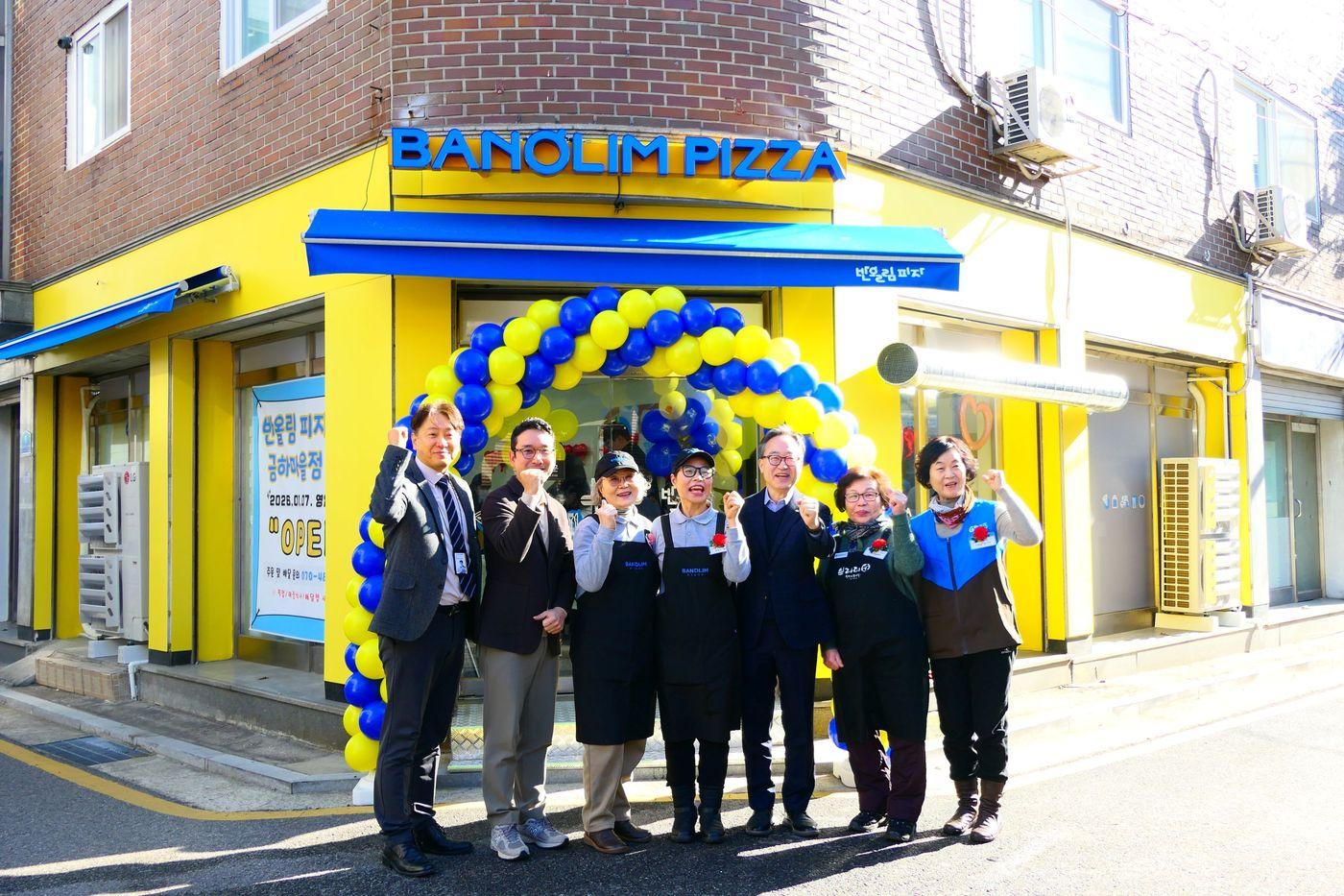 본문 이미지 - 반올림피자 서울금하마을점 오픈 행사. (왼쪽부터) 김선웅 금천시니어센터 관장, 한동효 ㈜피자앤컴퍼니 대표, (왼쪽에서 다섯 번째) 유성훈 금천구청장 등 관계자들이 기념촬영을 하고 있다.(반올림피자 제공)