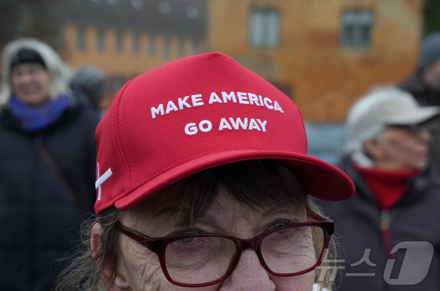본문 이미지 - 덴마크 수도 코펜하겐에서 미국의 그린란드 병합에 반대하는 시위자가 17일 '미국을 물러가게 하라'(Make America Go Away)라고 쓰인 모자를 쓰고 있다. 2026.1.17 ⓒ 로이터=뉴스1 ⓒ News1 강민경 기자