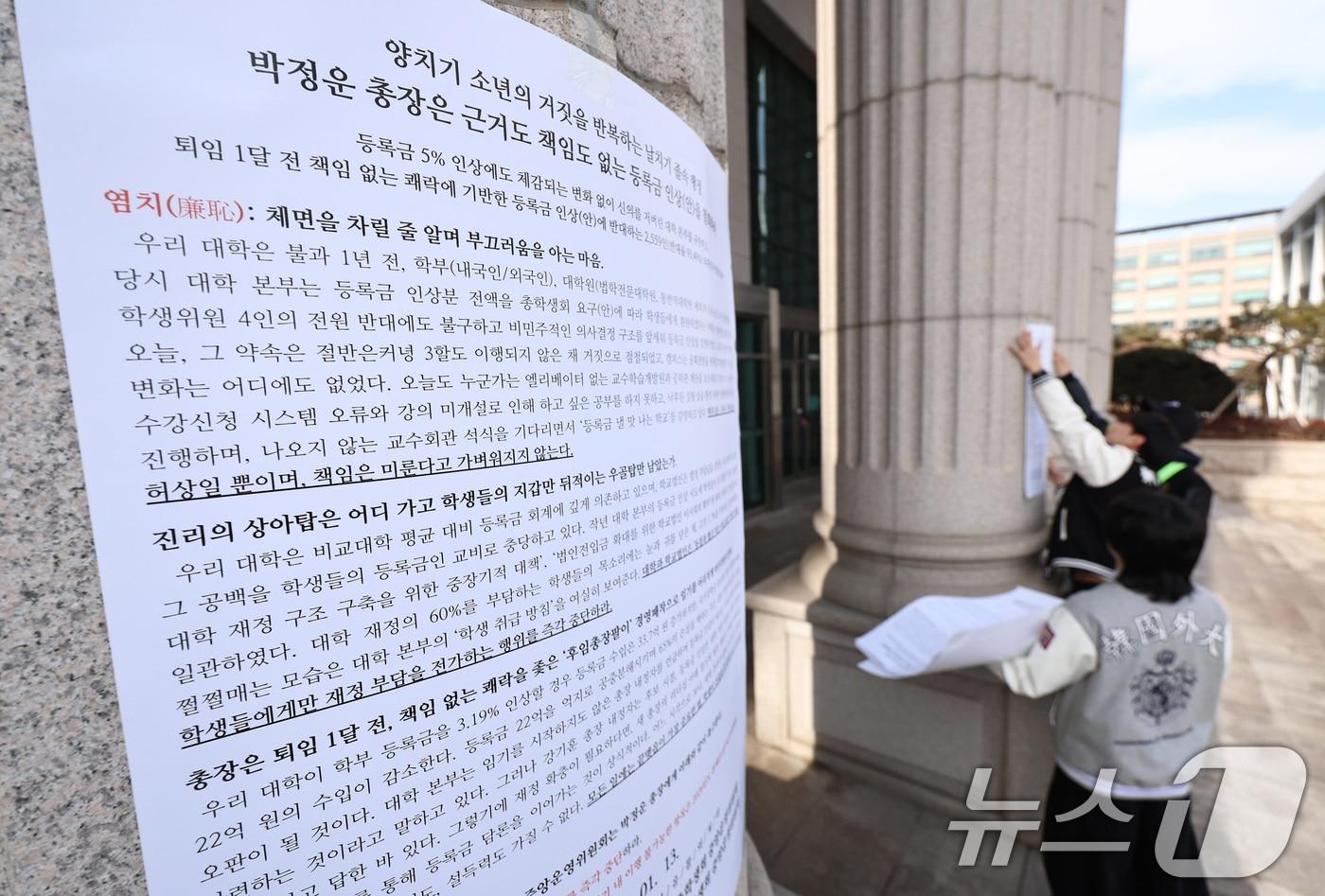 본문 이미지 - 한국외국어대학교 총학생회를 비롯한 학생들이 19일 오후 서울 동대문구 한국외대에서 학교 측이 제시한 올해 3.19%의 등록금 인상안에 항의하는 내용의 대자보를 붙이고 있다. 2026.1.19/뉴스1 ⓒ News1 구윤성 기자