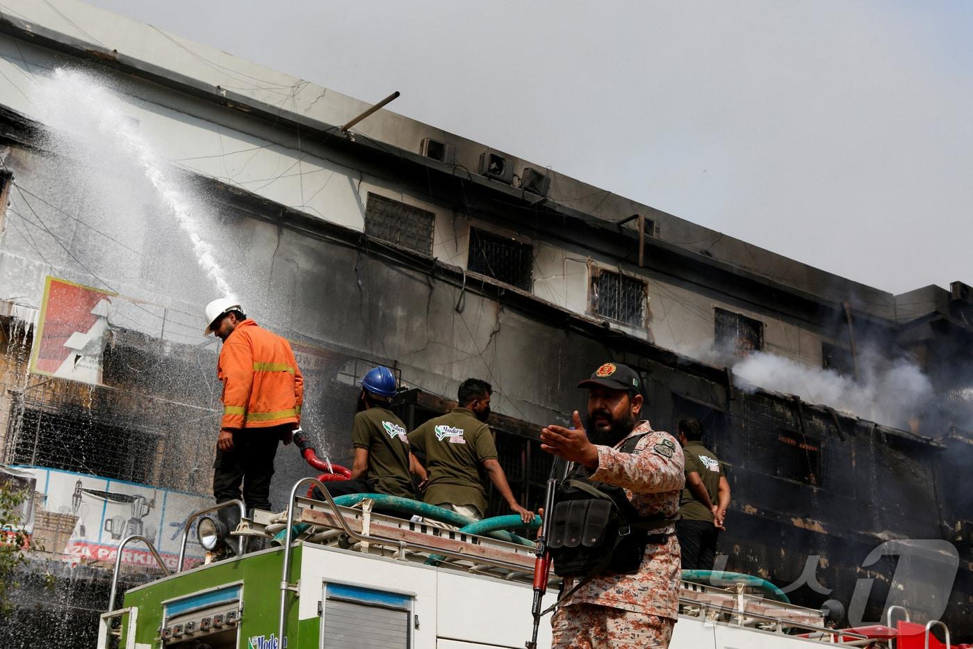 본문 이미지 - 18일 파키스탄 카라치의 굴 플라자 쇼핑센터에서 발생한 대형 화재를 진압하기 위해 소방관들이 물을 뿌리고 있다.2026.01.18.ⓒ 로이터=뉴스1