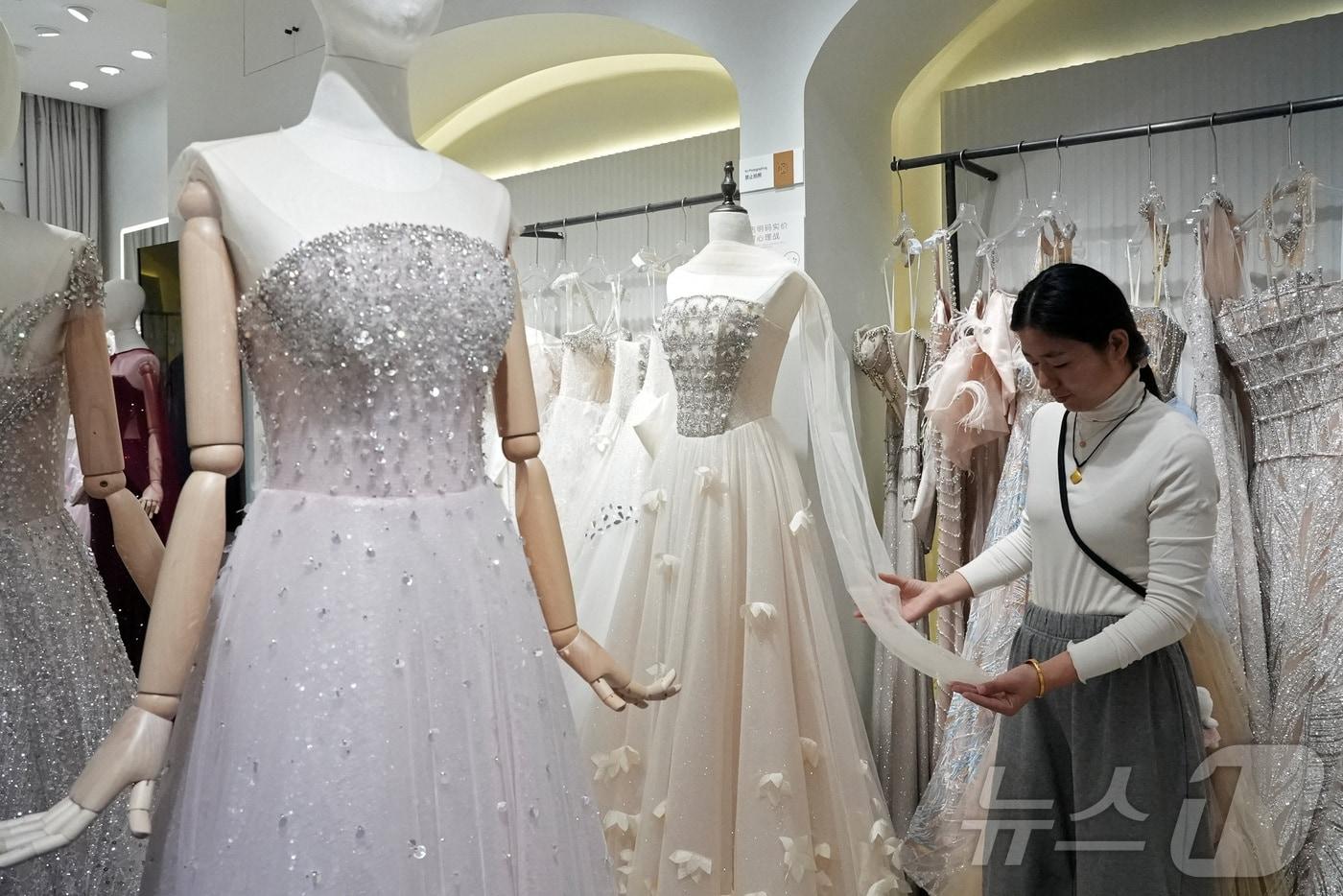 본문 이미지 - 16일(현지시간) 중국 장쑤성 쑤저우의 한 웨딩드레스 판매상이 드레스 원단을 살펴보고 있다. 중국의 출생아 수가 지난해 사상 최저치를 기록하며 인구 감소가 4년 연속 이어지고 있다. 2026. 01. 16. ⓒ 로이터=뉴스1 ⓒ News1 양은하 기자