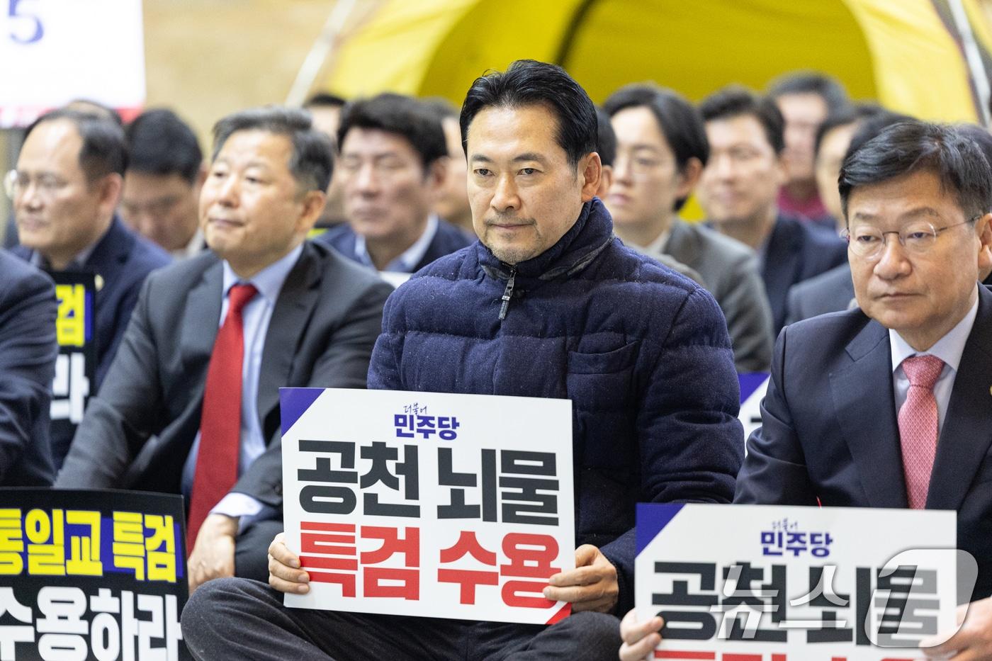 본문 이미지 - 장동혁 국민의힘 대표가 19일 서울 여의도 국회 로텐더홀에서 열린 통일교 게이트·더불어민주당 공천뇌물 특검 촉구 규탄대회에 참석해 피켓을 들고 있다. 2026.1.19/뉴스1 ⓒ News1 이승배 기자