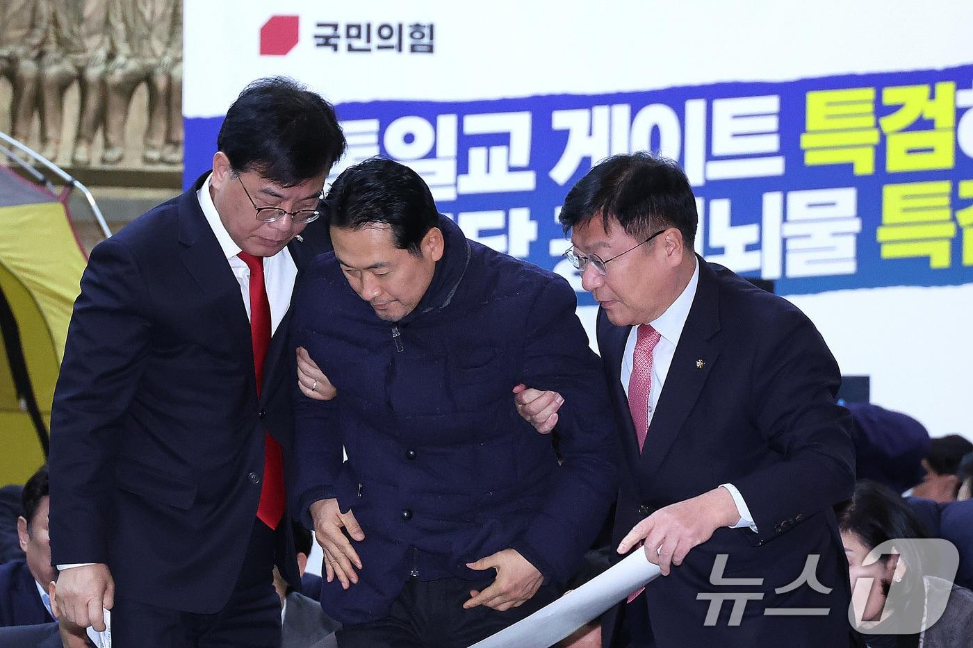 본문 이미지 - 장동혁 국민의힘 대표가 19일 서울 여의도 국회 로텐더홀에서 열린 통일교 게이트·더불어민주당 공천뇌물 특검 촉구 규탄대회를 마친 후 송언석 원내대표 등의 부축을 받고 있다. 2026.1.19/뉴스1 ⓒ News1 신웅수 기자