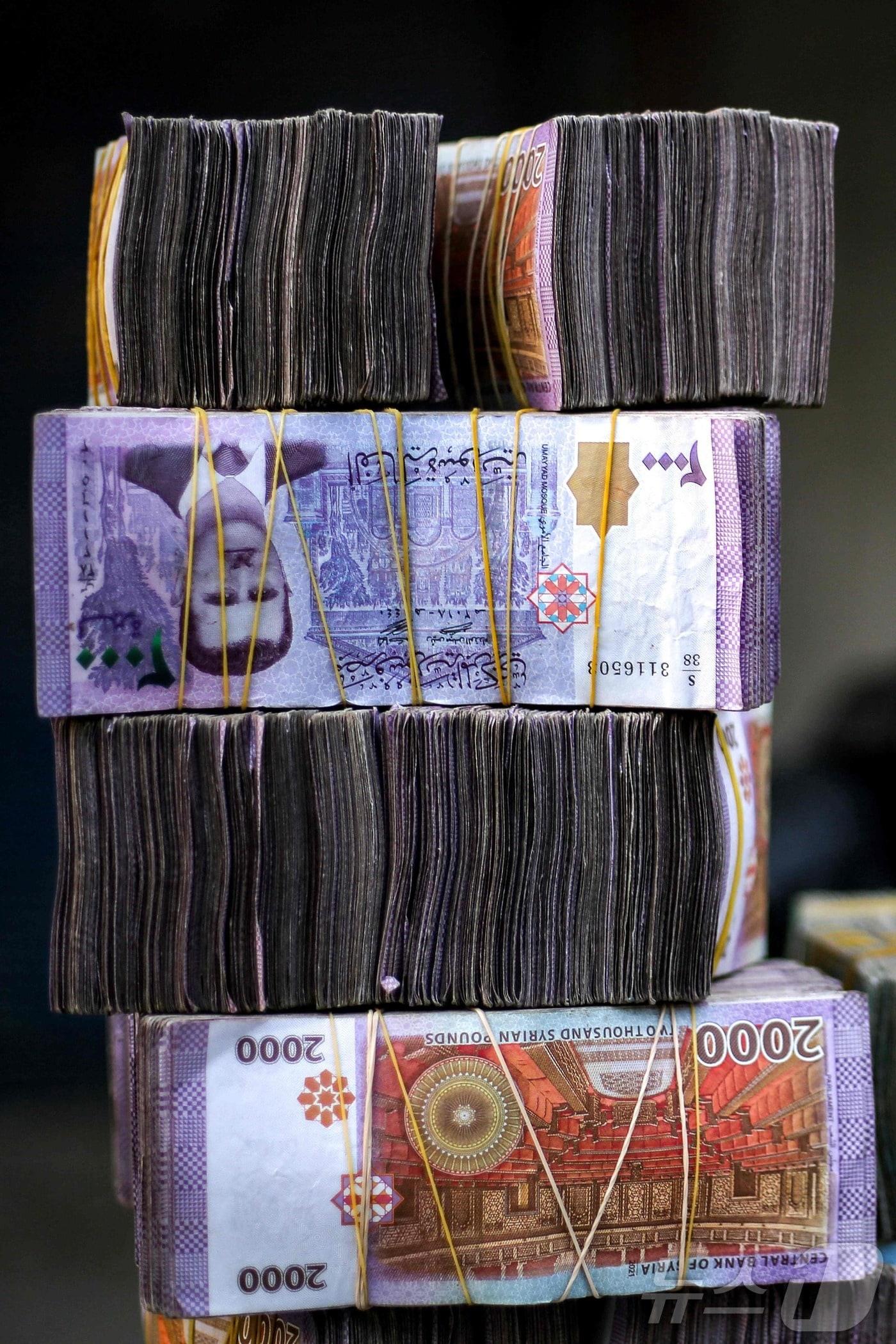 본문 이미지 - 시리아 동부 만비즈의 한 시장 내 환전상 가판대 위에 시리아 파운드화가 쌓여있다. 2025.1.4./뉴스1 ⓒ AFP=뉴스1 ⓒ News1 이창규 기자