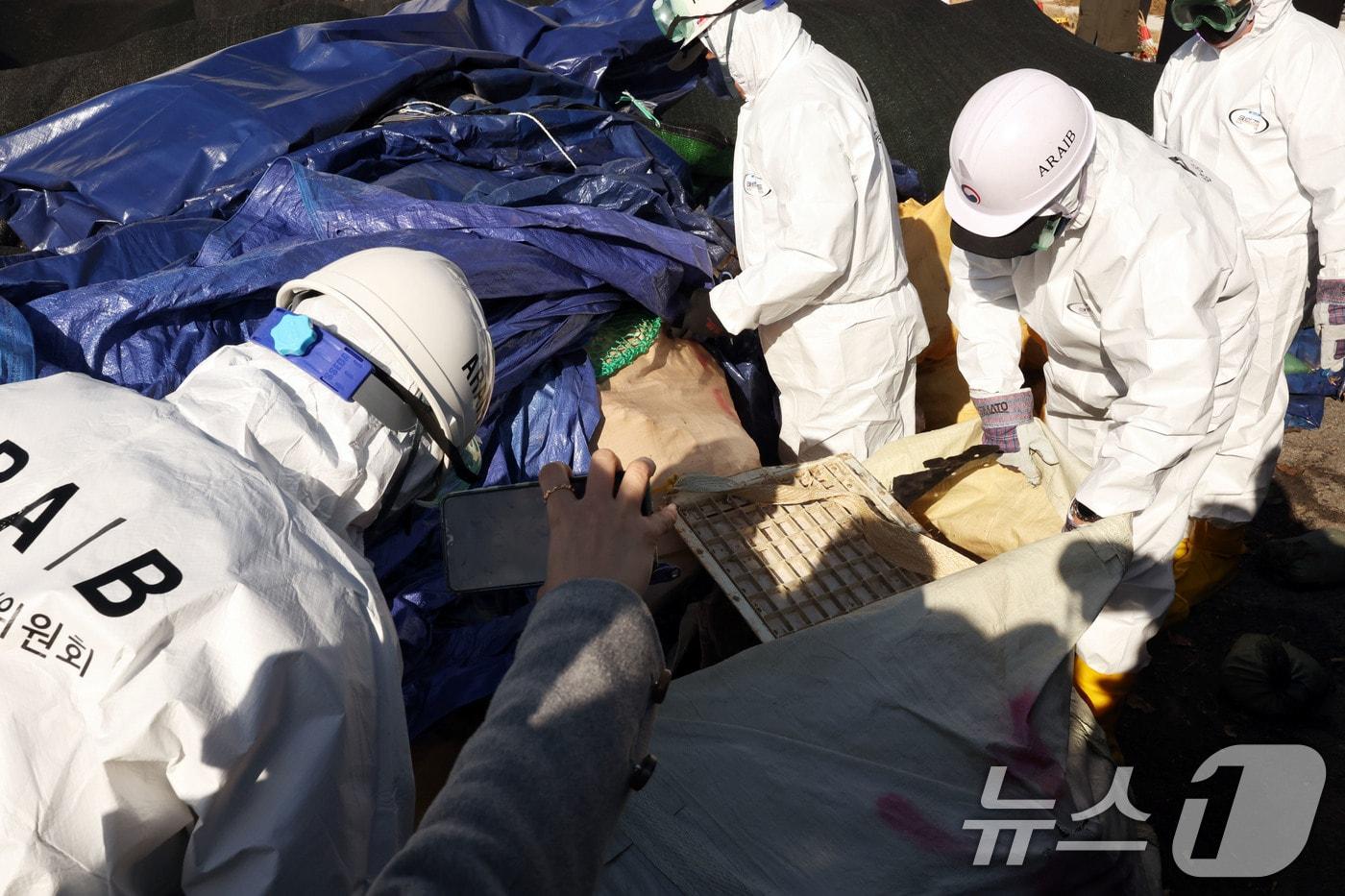 본문 이미지 - 20일 무안국제공항에서 열린 12·29 여객기 참사 진상규명을 위한 국정조사 특별위원회 현장조사에서 공항 관계자들이 기체잔해물이 보관된 사고 잔해보관소에서 방수포를 들어 내용물을 보여주고 있다. 2026.1.20./뉴스1 ⓒ 뉴스1 박지현 기자