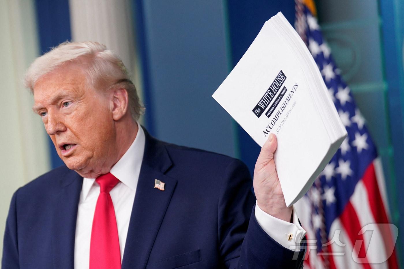 본문 이미지 - 도널드 트럼프 미국 대통령이 20일(현지시간) 워싱턴DC 백악관에서 두 번째 임기 1주년을 맞아 자신의 성과를 모은 문서를 들어 보이고 있다. 2026.01.20. ⓒ 로이터=뉴스1 ⓒ News1 