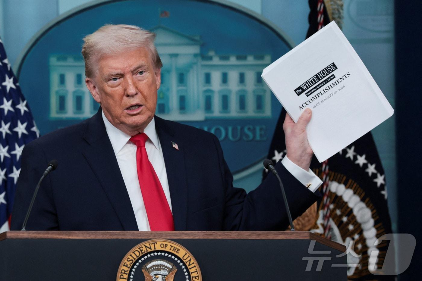 본문 이미지 - 도널드 트럼프 미국 대통령이 두 번째 임기 1주년을 맞은 20일(현지시간) 워싱턴DC 백악관에서 자신의 성과를 모은 문서를 들어 보이고 있다. 2026.01.20. ⓒ 로이터=뉴스1 ⓒ News1 류정민 특파원